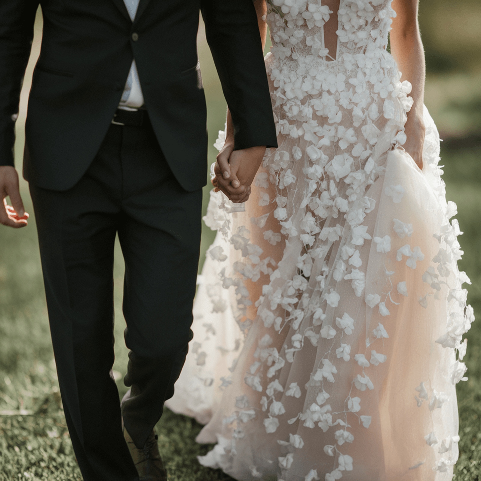 Cropped wedding couple walking together through grass