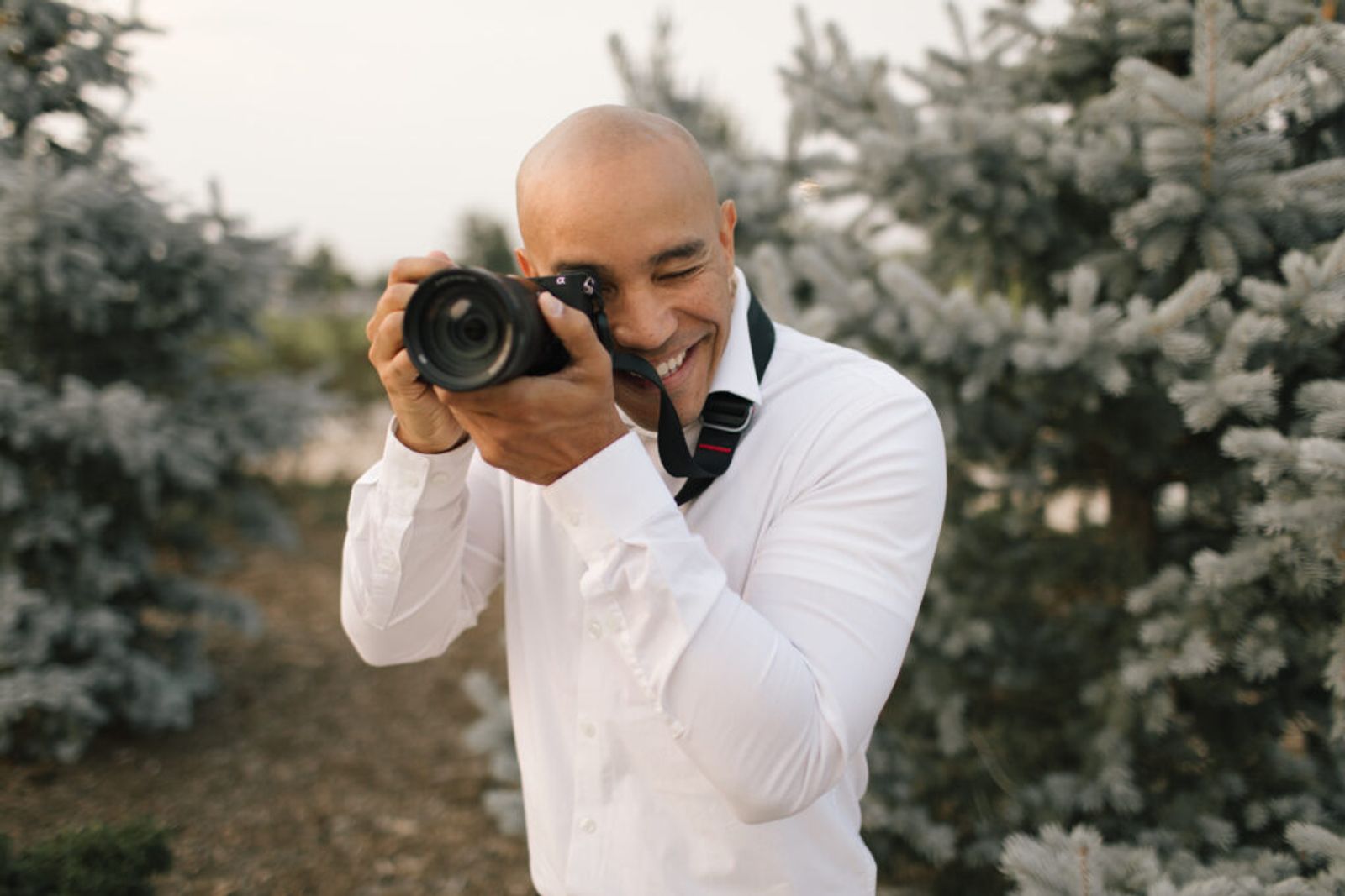 Person smiling while aiming a camera outdoors