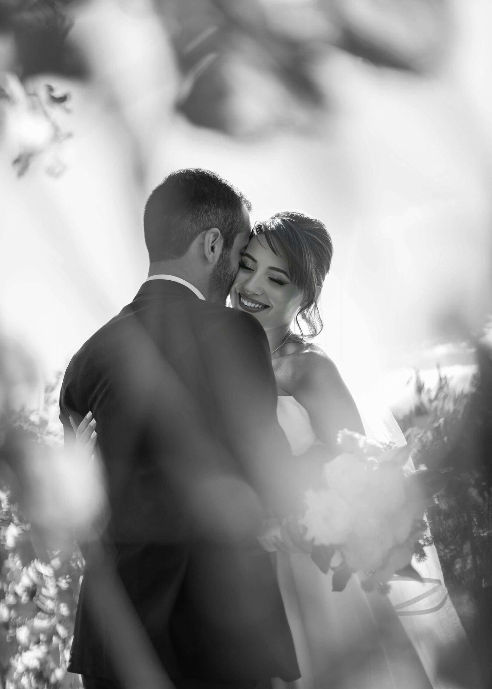 Veiled Embrace Black-and-white wedding couple embracing beneath a veil