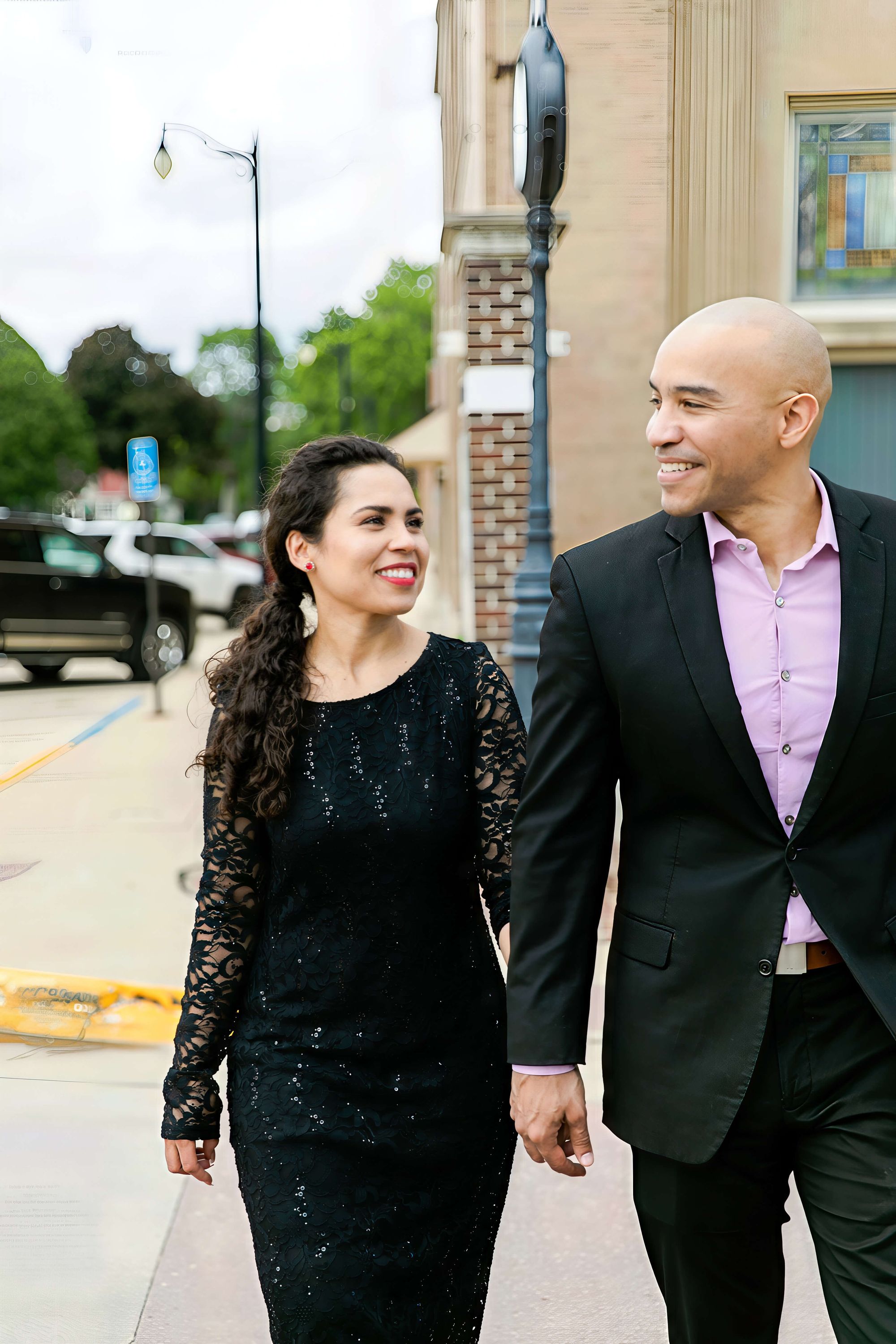 Sidewalk Walk Woman in a black lace dress and man in a dark jacket walking together on a sidewalk.