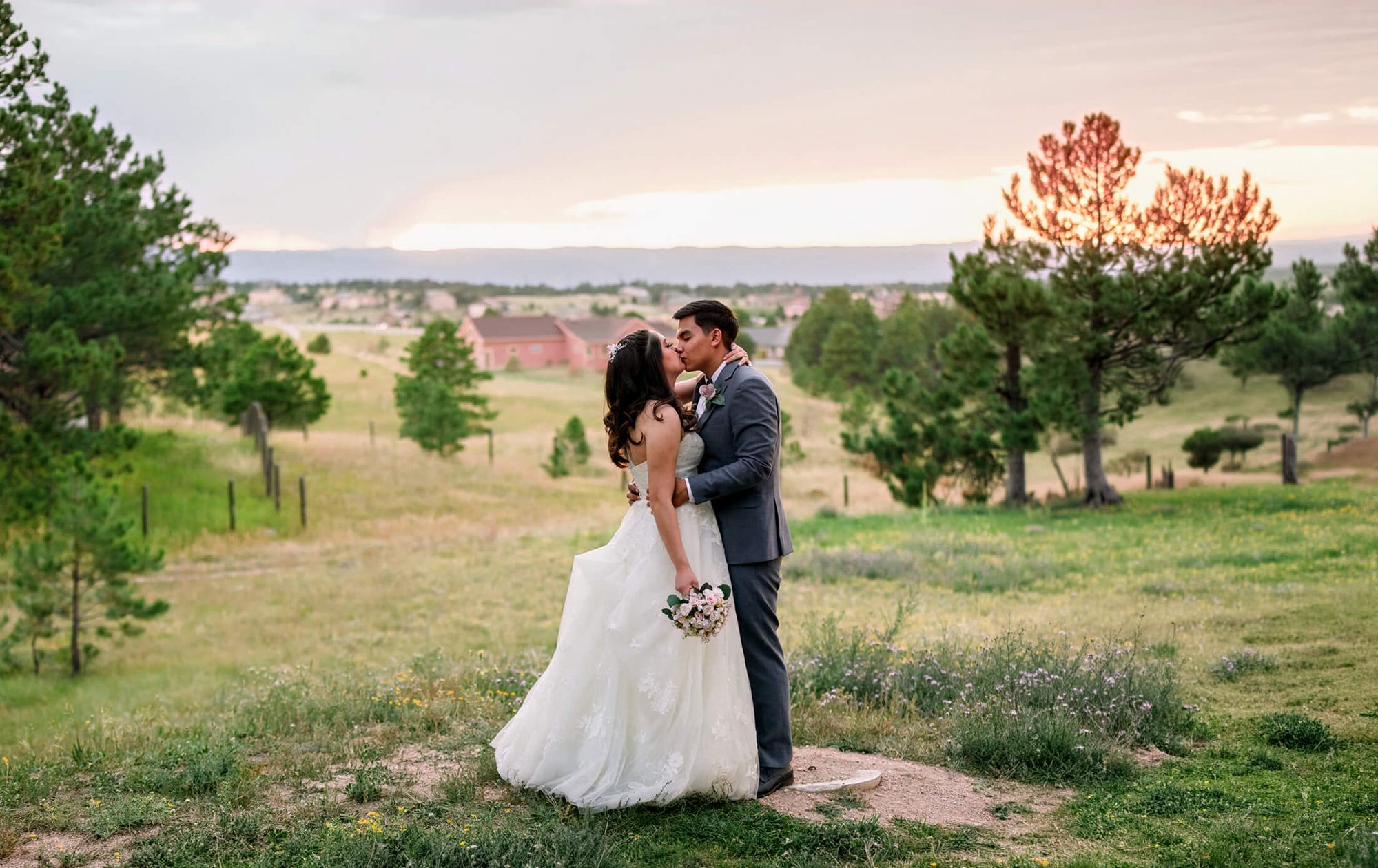 Sunset Field Embrace Two formally dressed people embracing in an open grassy landscape at sunset.