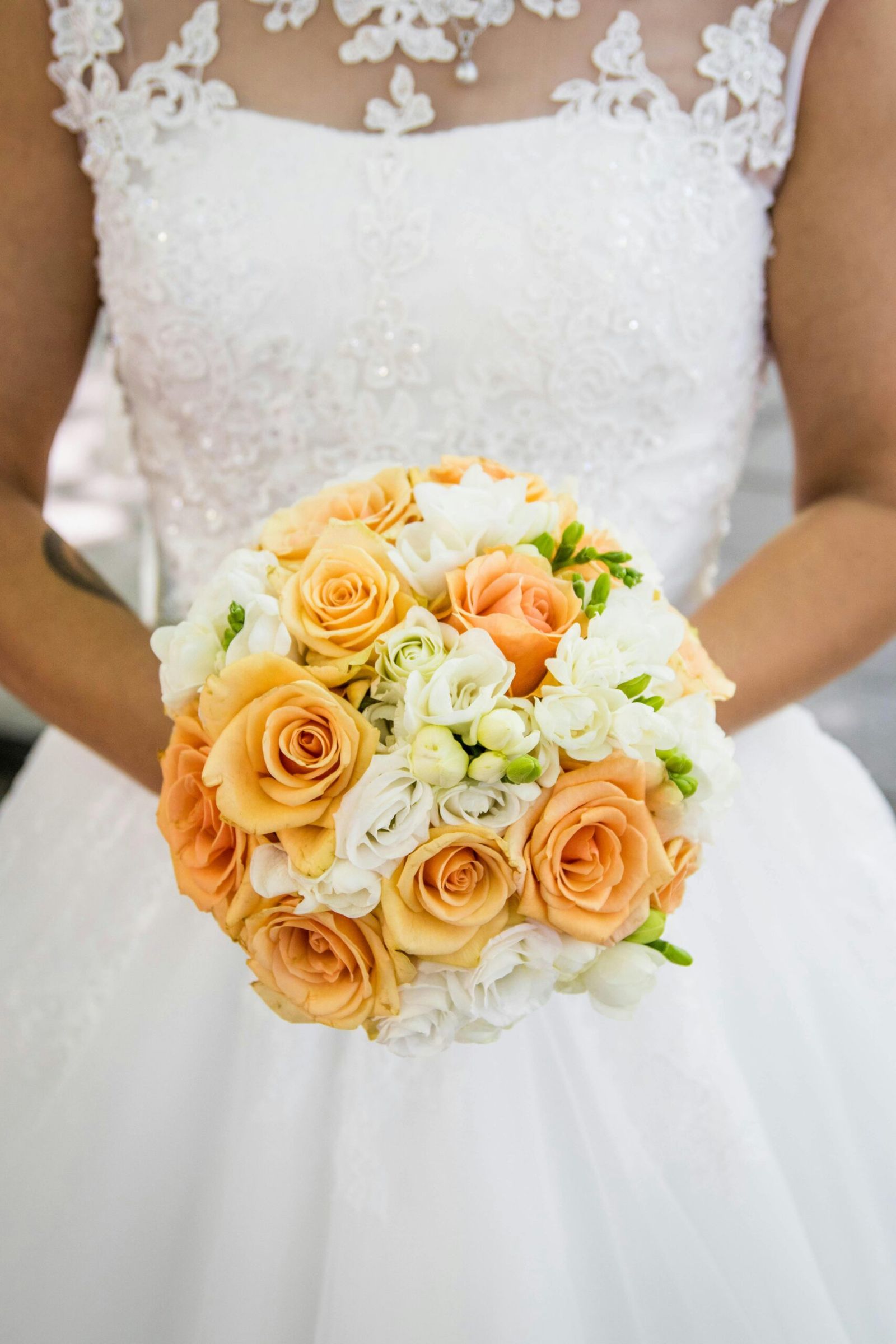 Orange Rose Bouquet Orange and cream rose bouquet held against a white dress