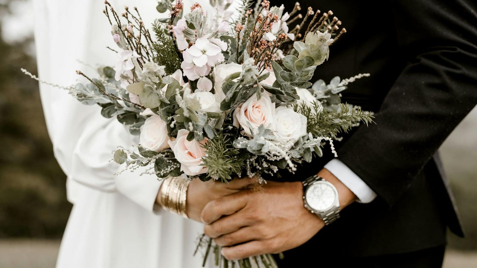 White Bouquet Person in a dark suit holding a large white-and-green bouquet