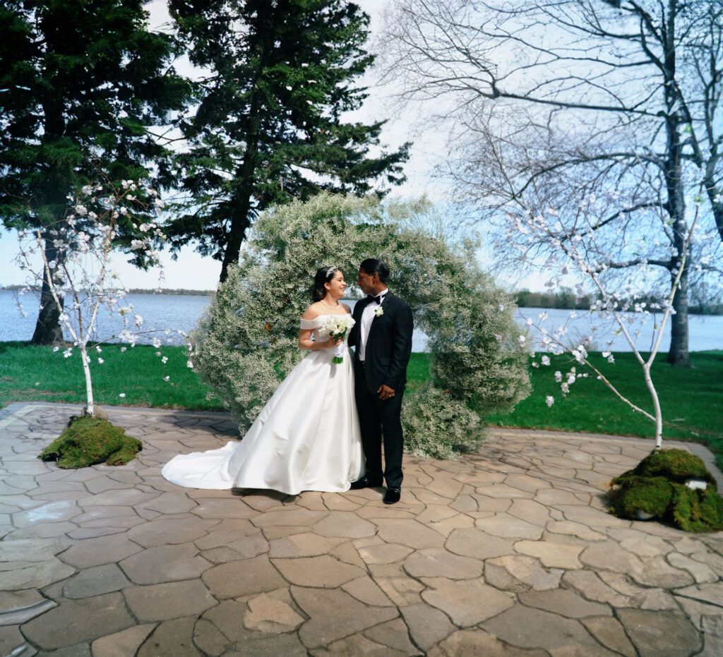 Waterside Garden Couple Wedding couple standing beneath flowering trees beside water