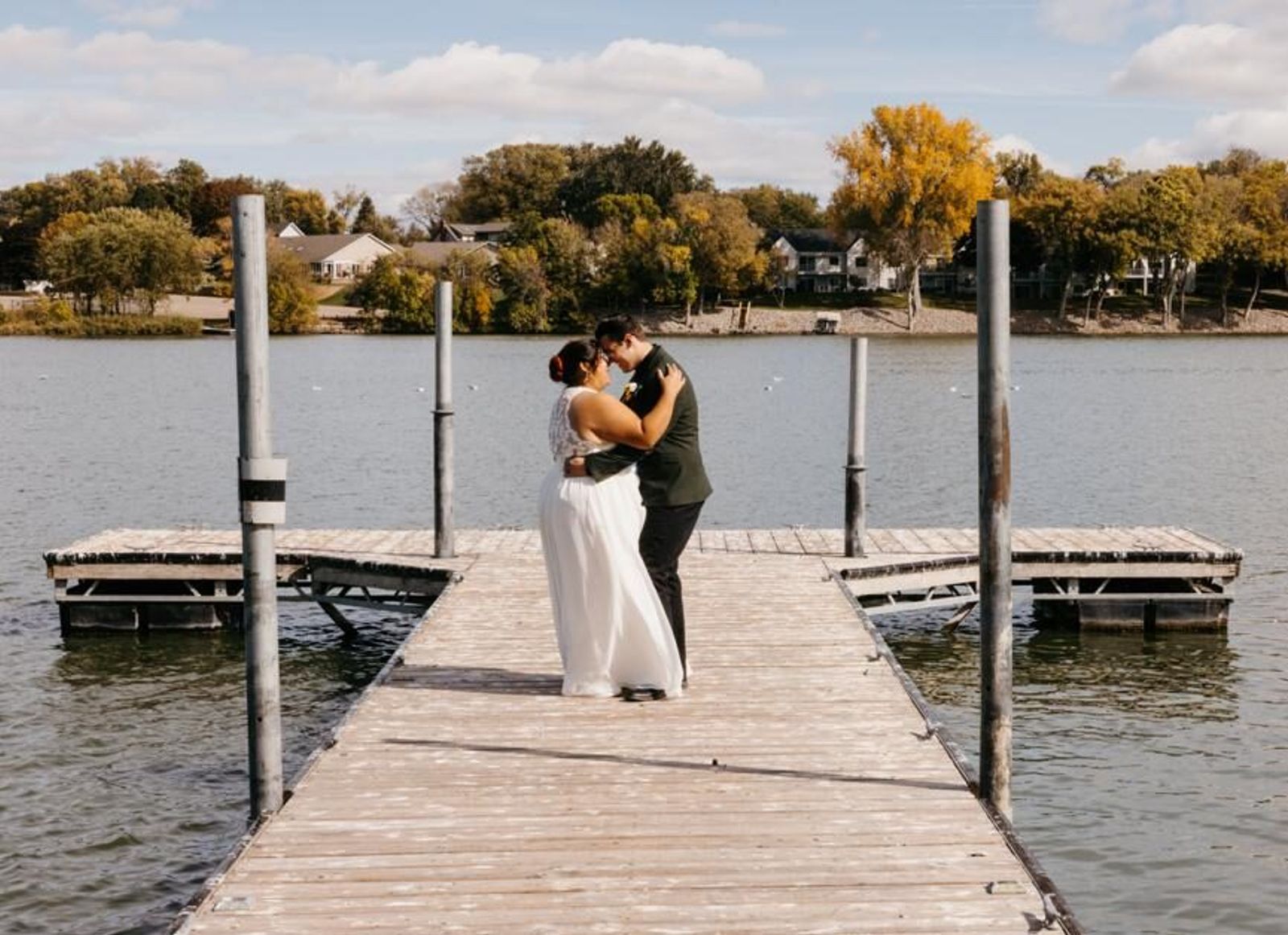Wedding couple embracing on a wooden dock beside water