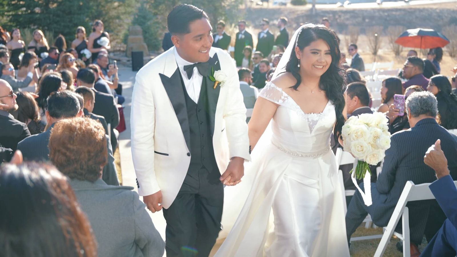 Wedding couple walking hand in hand through seated guests