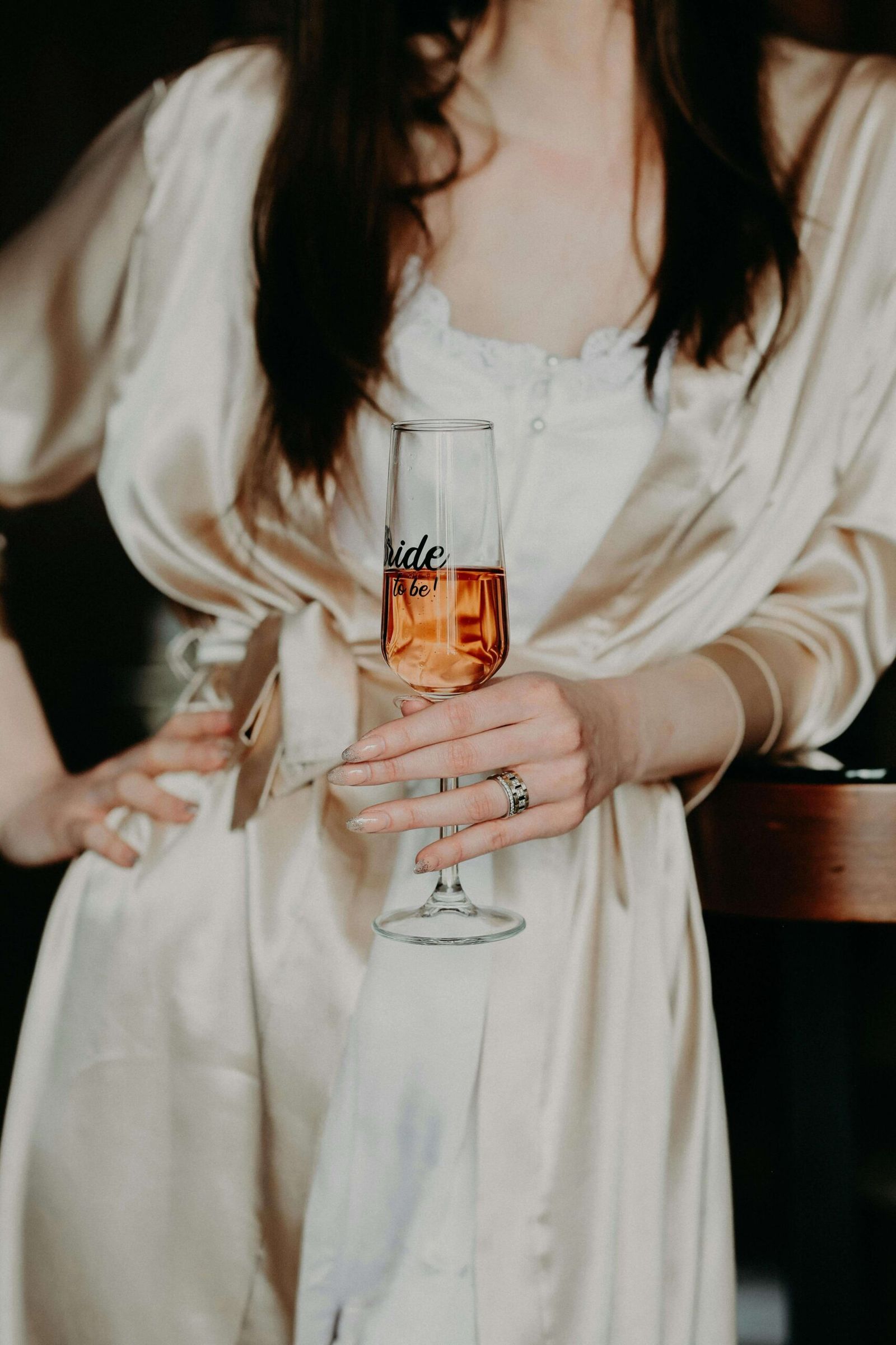 Cropped person in a white robe holding a champagne glass