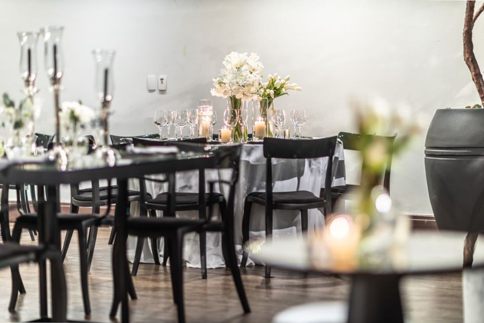 Minimal reception room with dark tables pale flowers and glassware