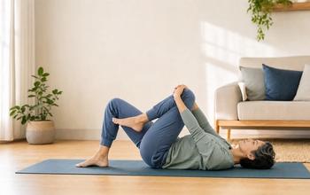 An adult gently bringing one knee toward the chest while lying on an exercise mat.