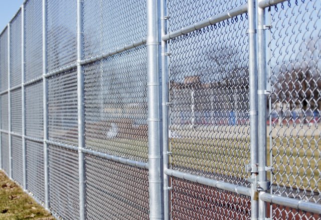 A tall chain-link fence in a grassy recreation area