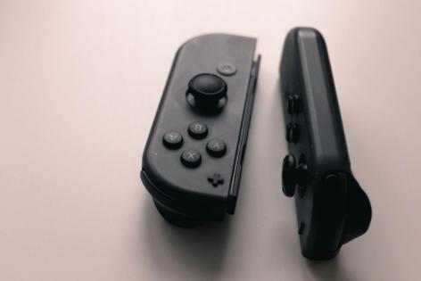 Two black original Nintendo Switch Joy-Con controllers resting on a pale surface.