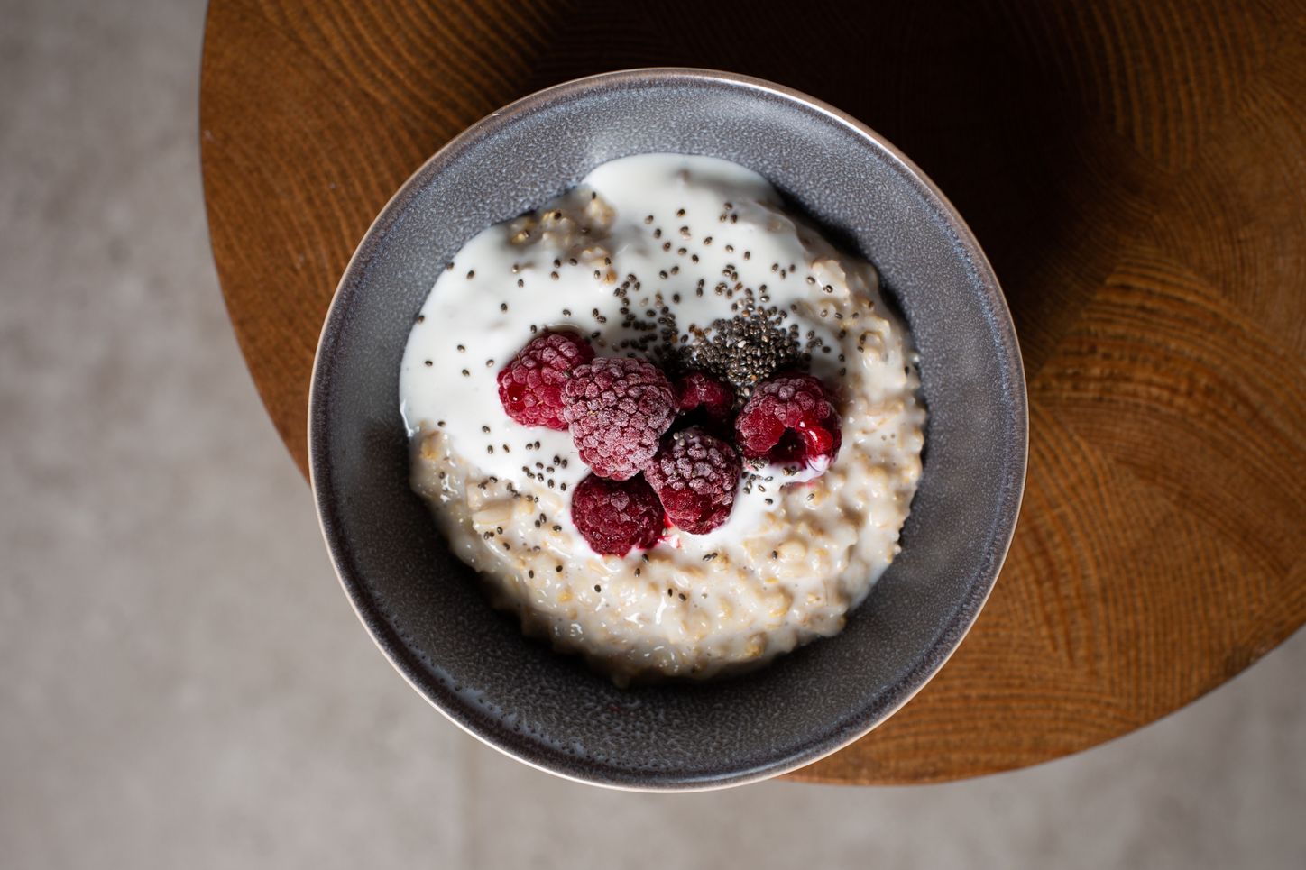 A bowl of oatmeal topped with yogurt, chia, and raspberries.