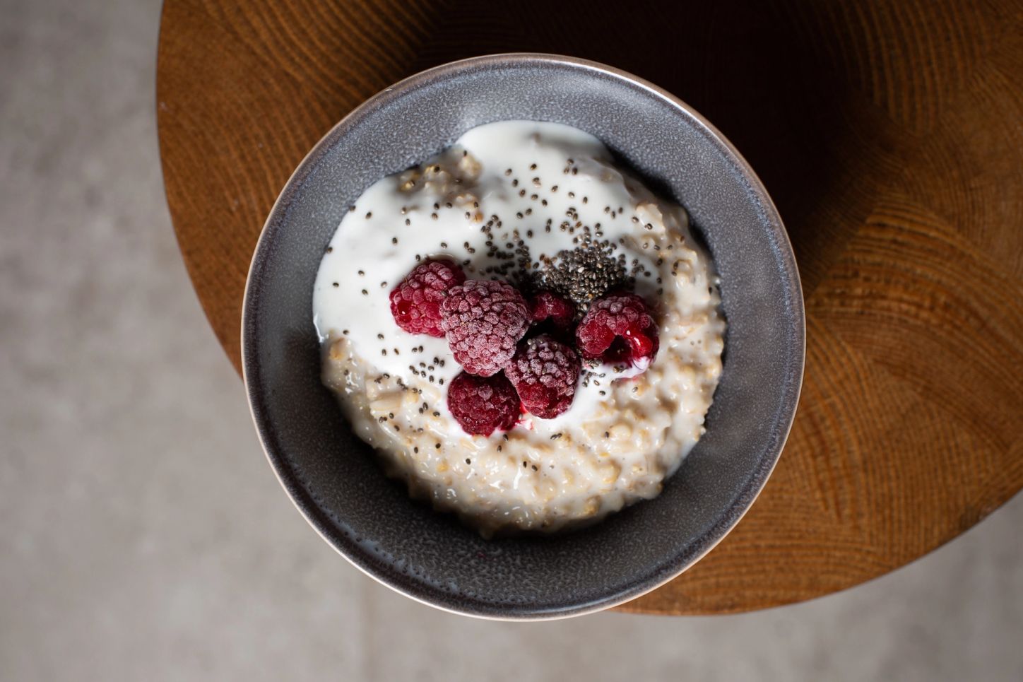 A bowl of oatmeal topped with yogurt, chia, and raspberries.