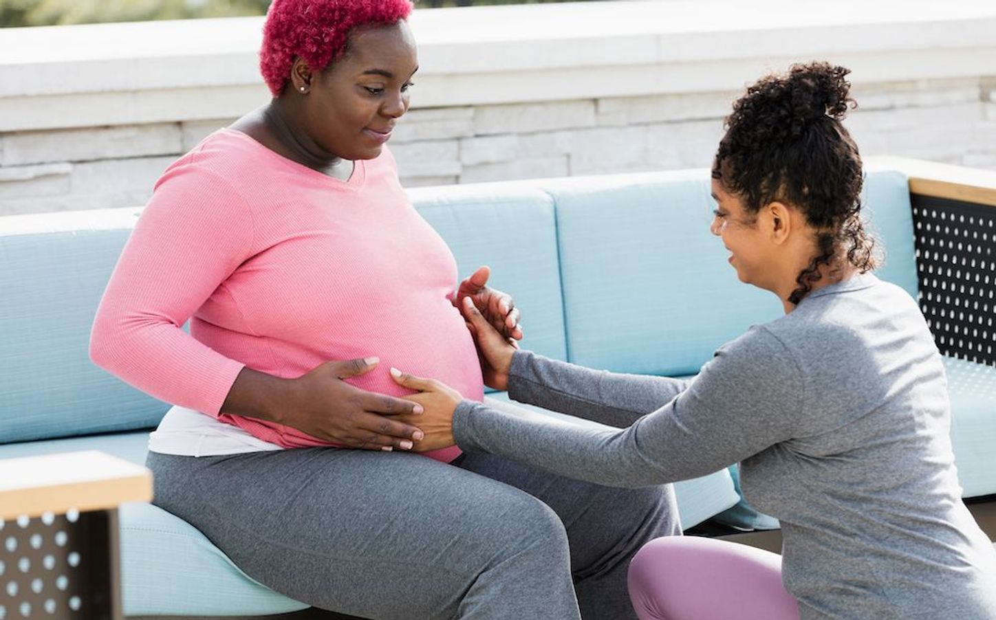 A doula places her hands on a pregnant person's belly.