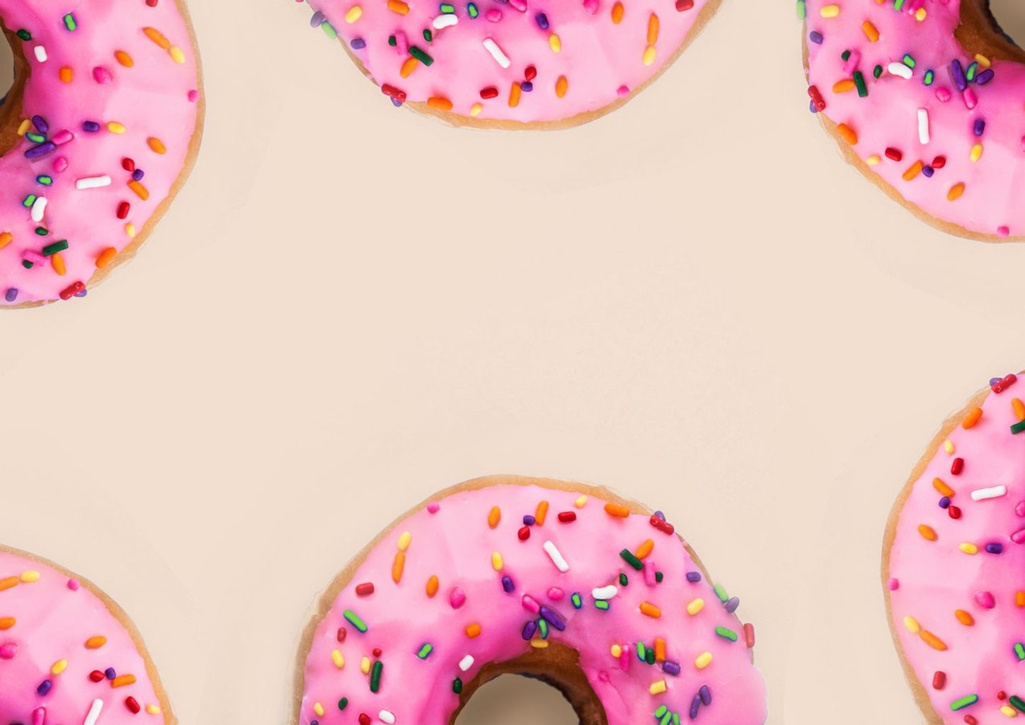 Six pink donuts line the edge of a cream-colored background.
