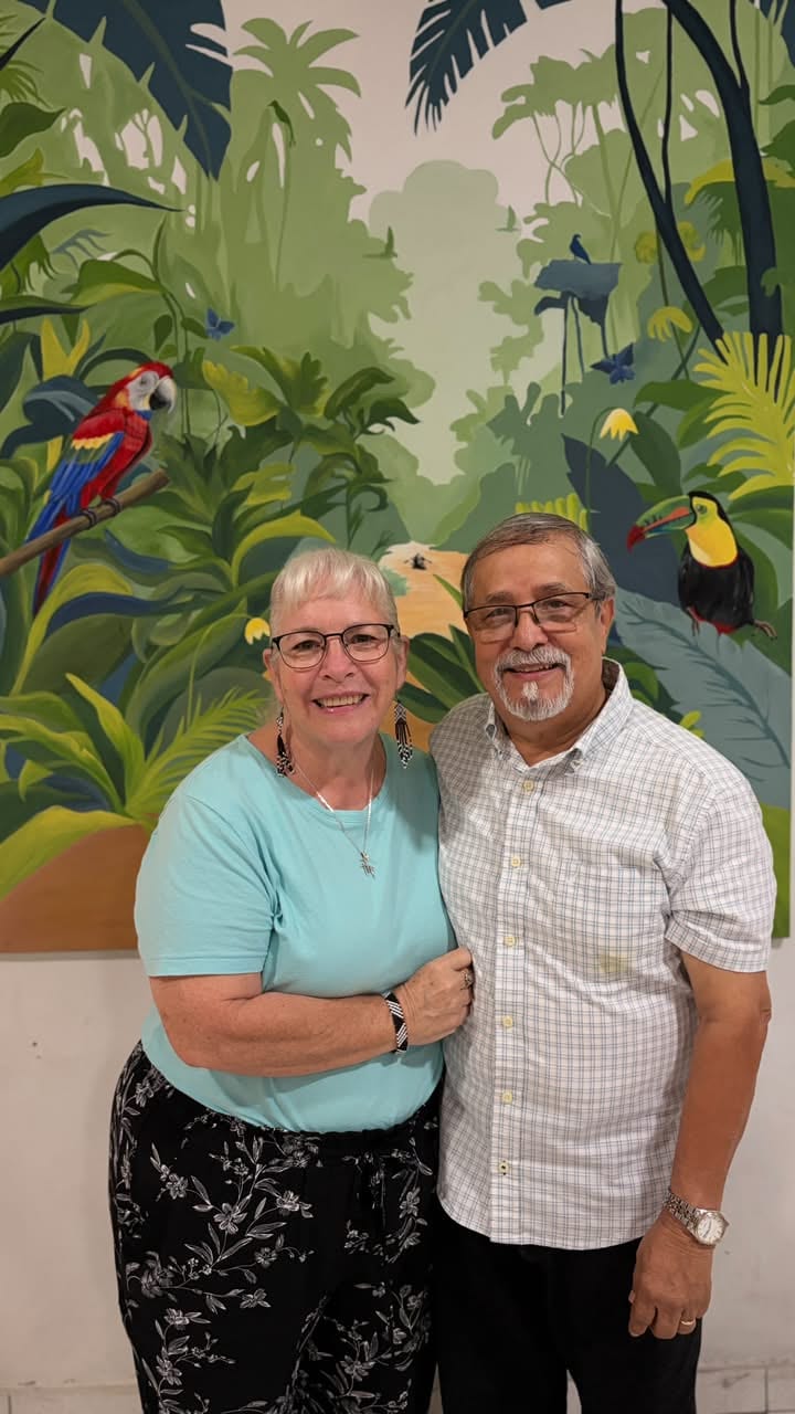 Jaime y Lori Useche, directores fundadores de JUCUM Leticia, abrazados frente a un mural de la selva