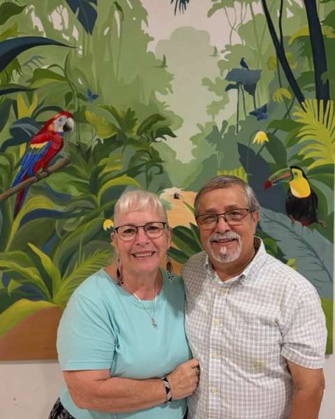 Jaime y Lori Useche, directores fundadores de JUCUM Leticia, abrazados frente a un mural de la selva