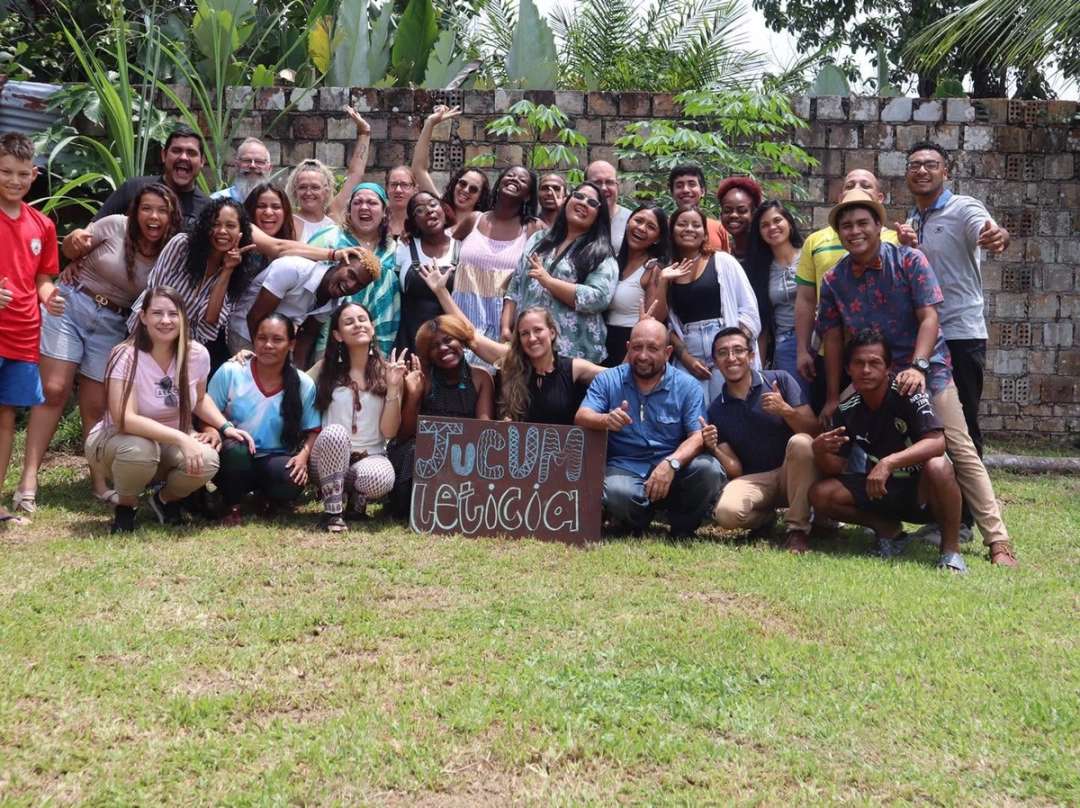 Gran grupo de misioneros al aire libre con un cartel de JUCUM Leticia, celebrando