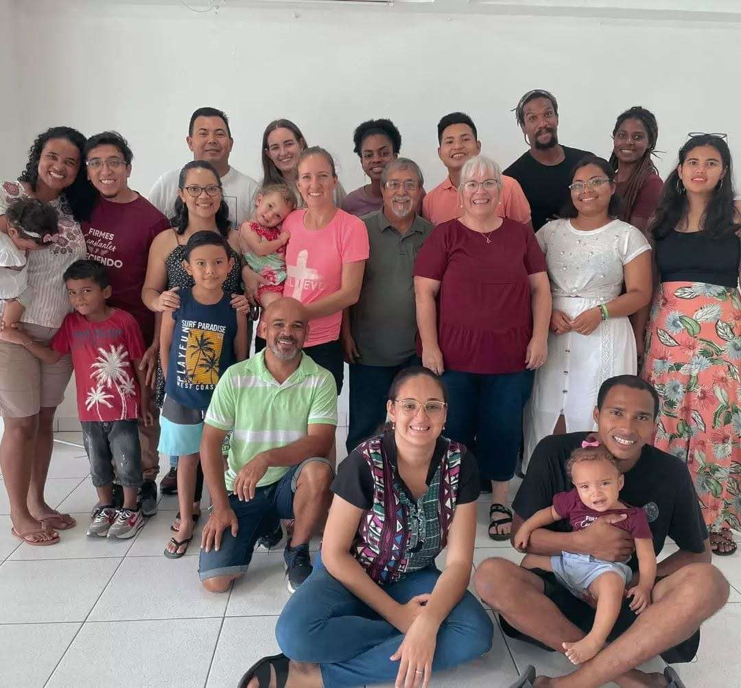 Un equipo de familias y misioneros posa sonriendo en una sala luminosa