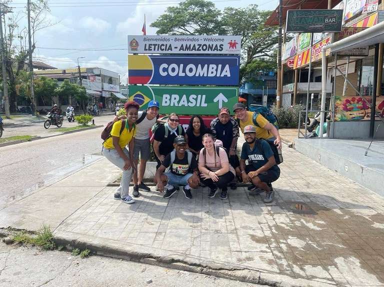 Un equipo misionero posa junto al letrero que señala Colombia, Brasil y Perú en Leticia