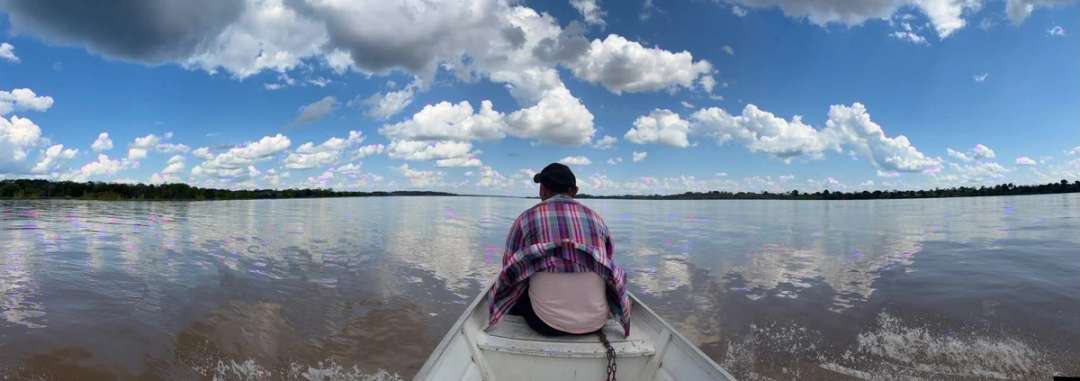 Un hombre navega en una canoa por el río Amazonas bajo un cielo de nubes