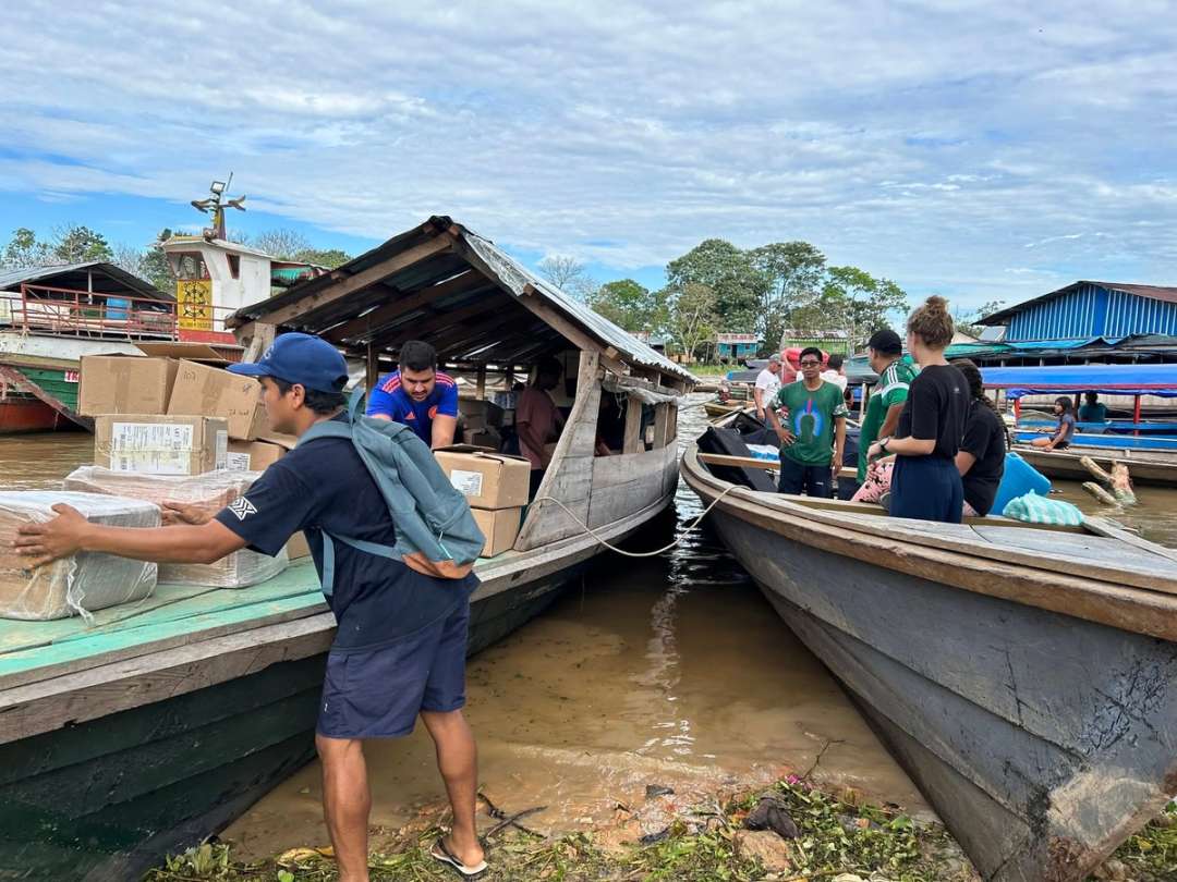 Voluntarios pasan cajas de Biblias a una lancha en el puerto fluvial