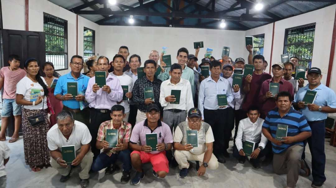 Líderes de comunidades muestran sus Biblias verdes en un salón de reuniones