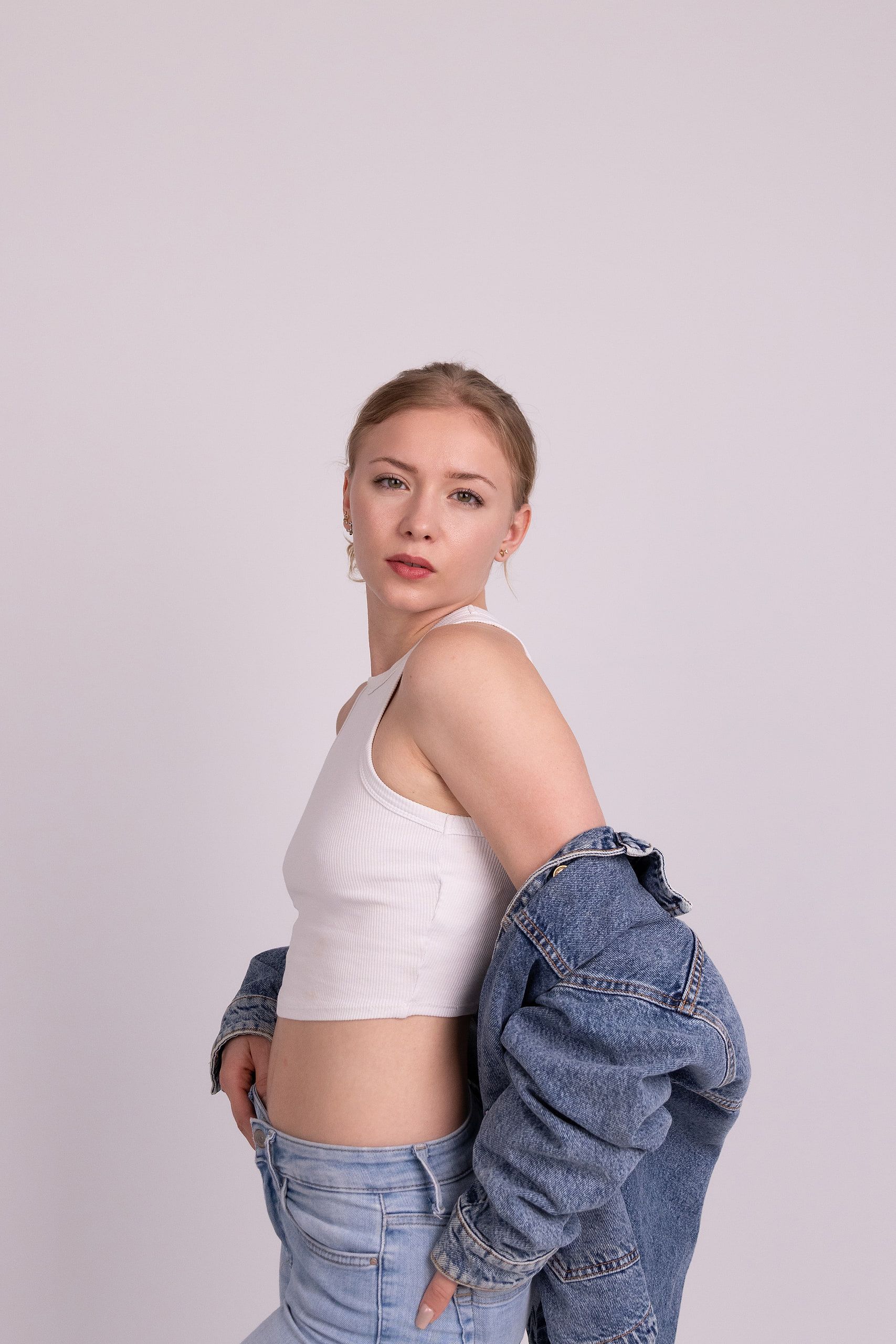 Fashion-Portrait: Annette im weißen Croptop und Jeans, die Jeansjacke locker gehalten.