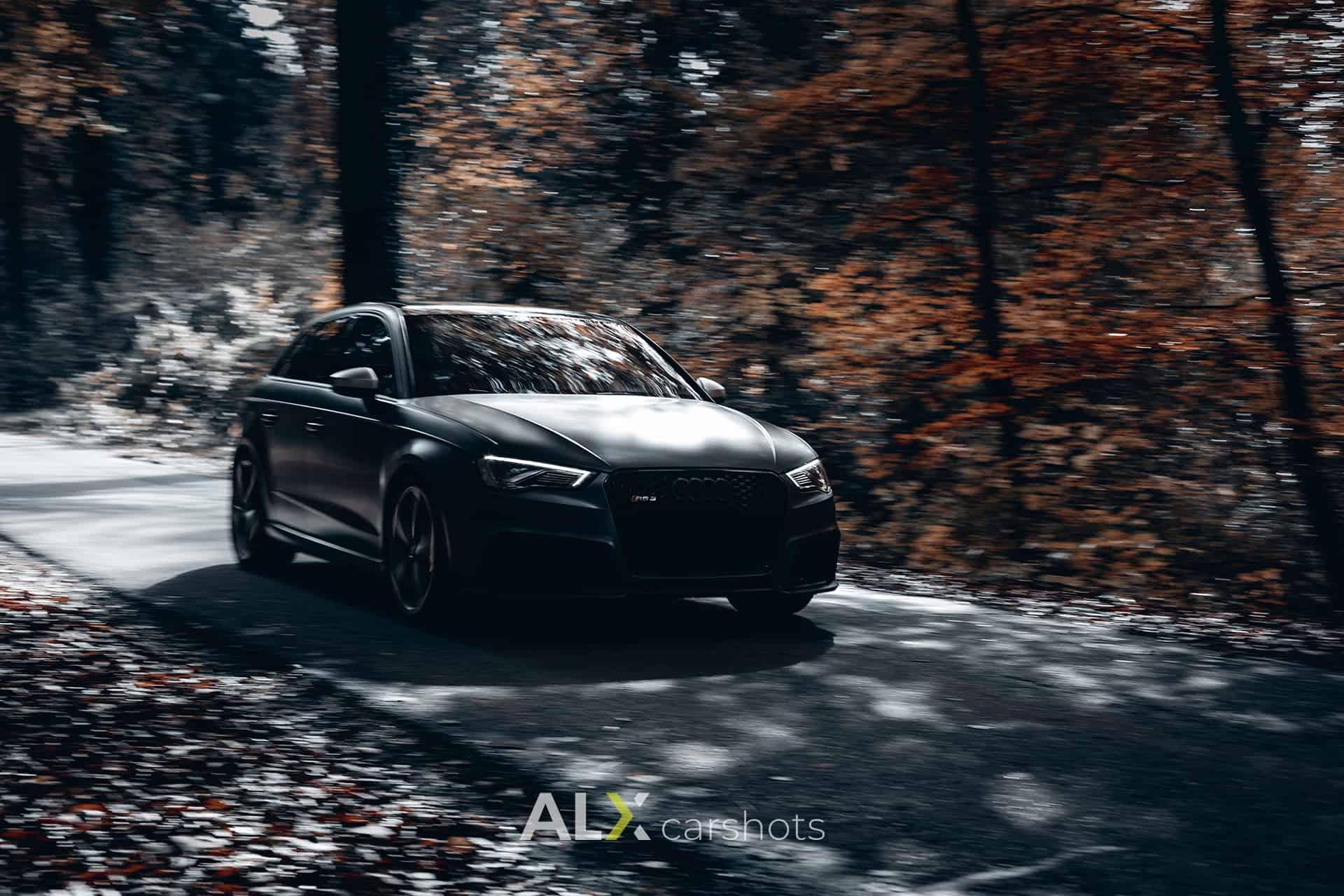Mitzieher eines dunklen Audi RS3 auf einer herbstlichen Waldstraße im Hochschwarzwald, Hintergrund verwischt