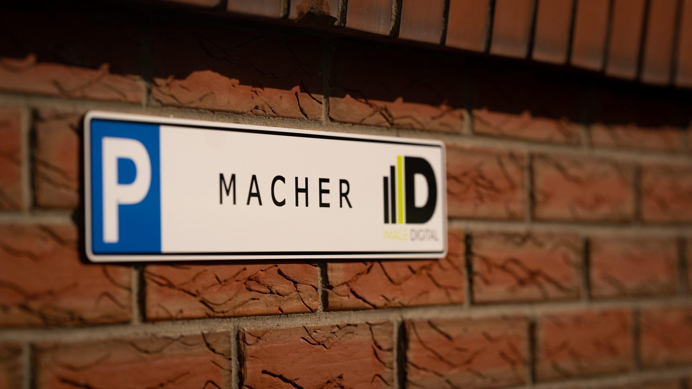 Parkschild an einer Klinkerwand mit der Aufschrift MACHER und dem ID-Logo von Image Digital.