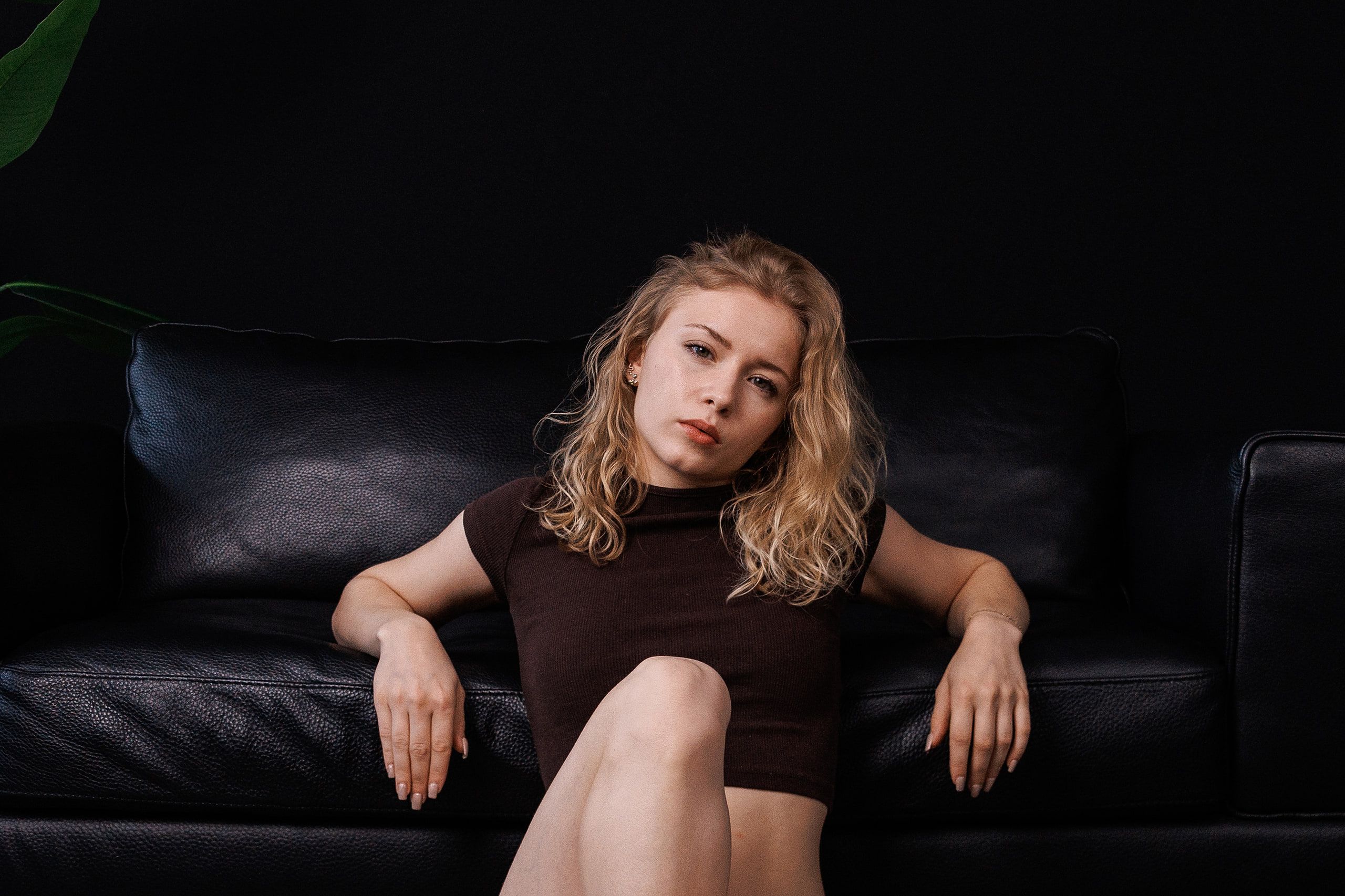 Editorial-Portrait: Annette auf einem schwarzen Ledersofa, braunes Oberteil, natürliche Pose.