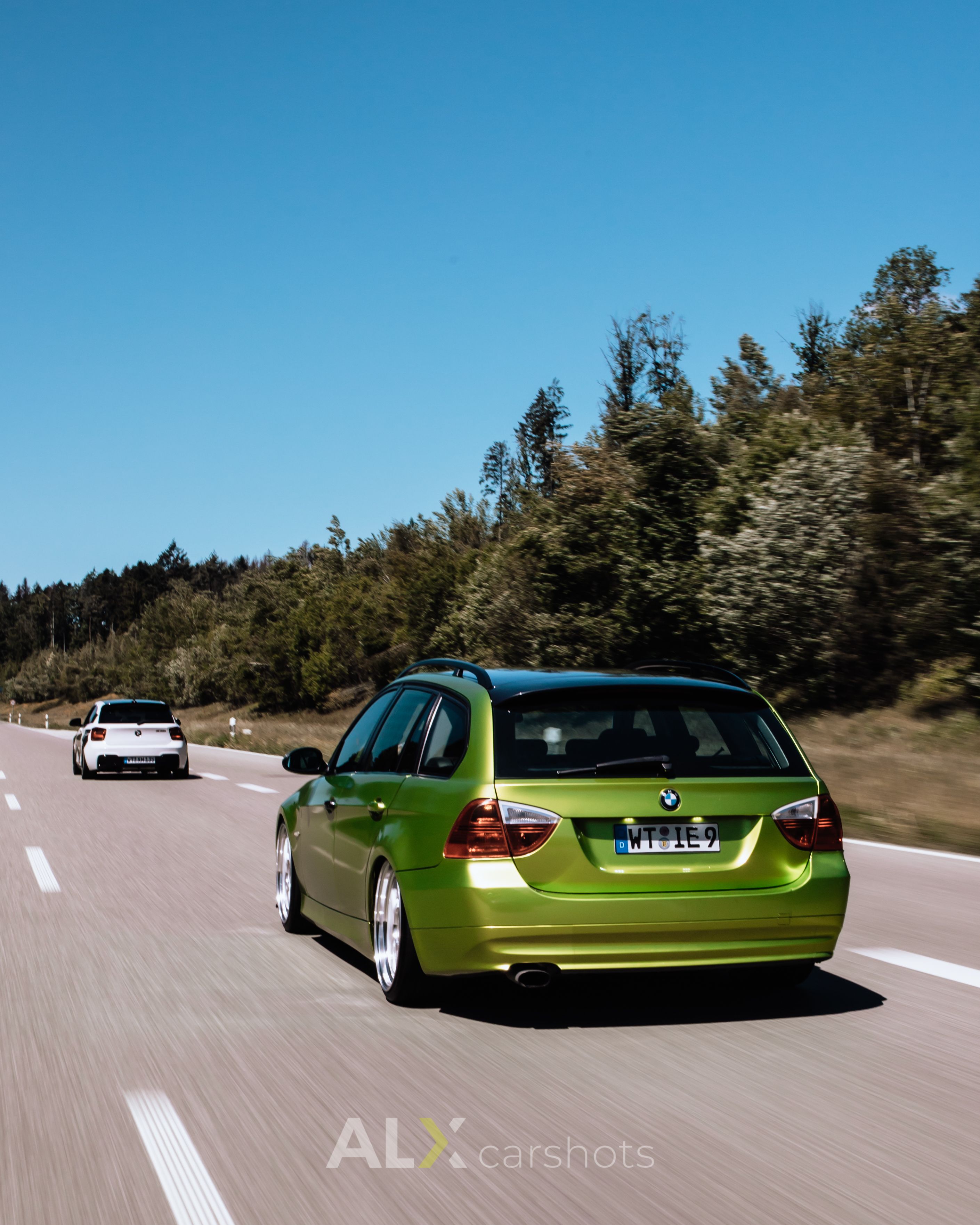 Grüner BMW 3er Touring als Rollingshot von hinten auf einer Landstraße im Schwarzwald mit Bewegungsunschärfe