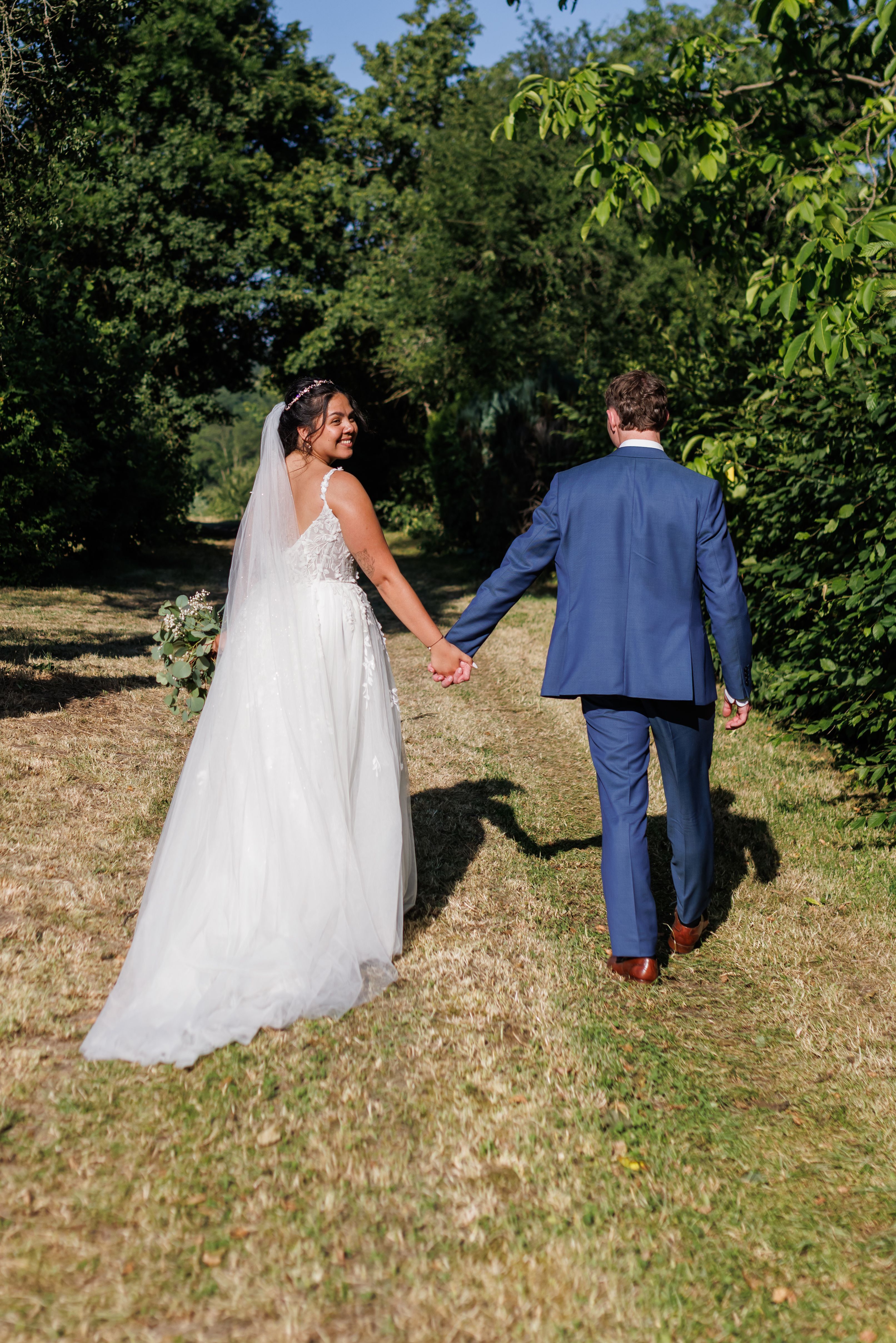 Stefanie und Manuel gehen Hand in Hand über einen grünen Weg davon