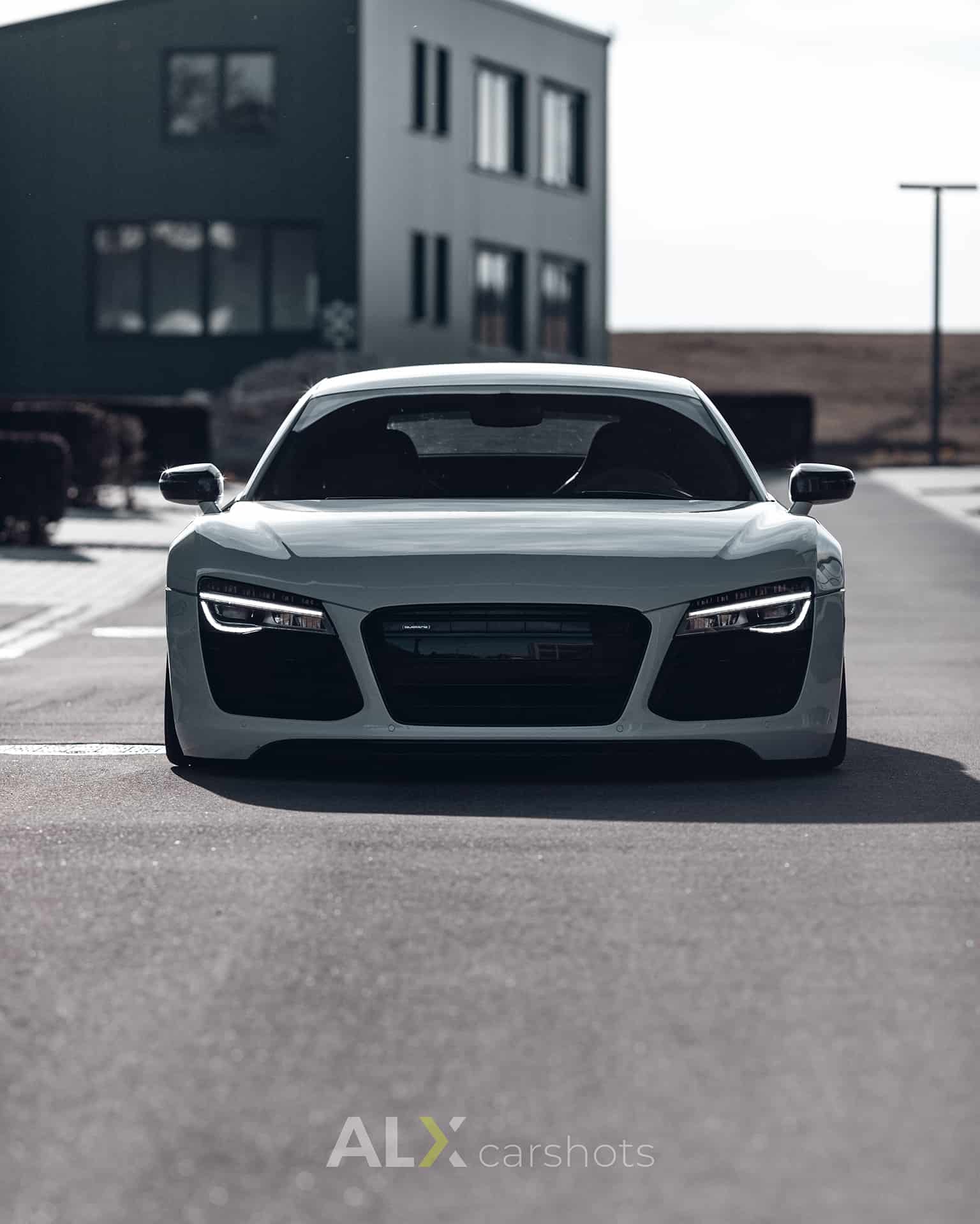 Weißer Audi R8 frontal auf der Straße eines Gewerbeparks am Bodensee, Kamera auf Scheinwerferhöhe