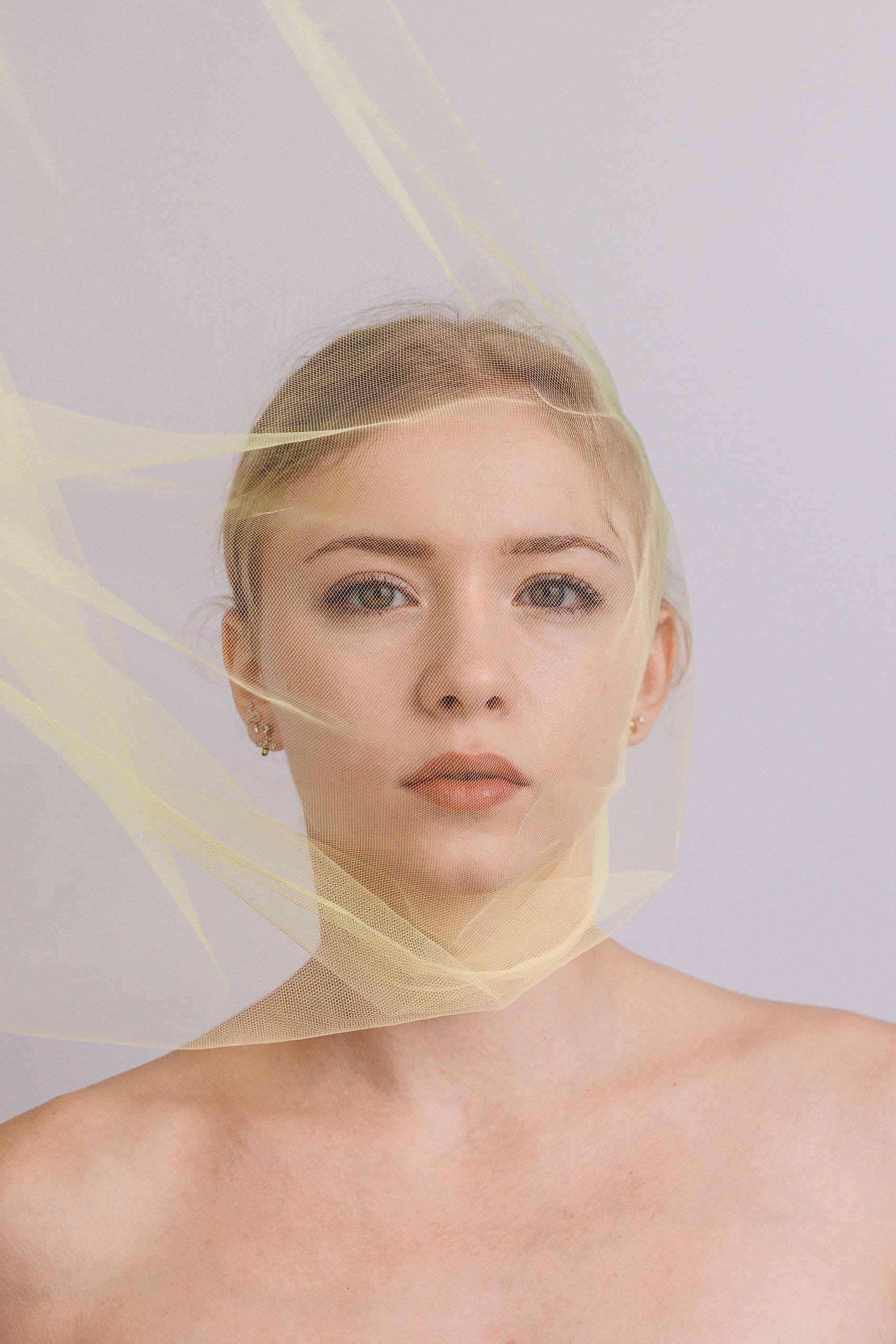Beauty-Portrait: Annette mit gelbem Tüll, der ihr Gesicht umspielt, vor hellem Hintergrund.