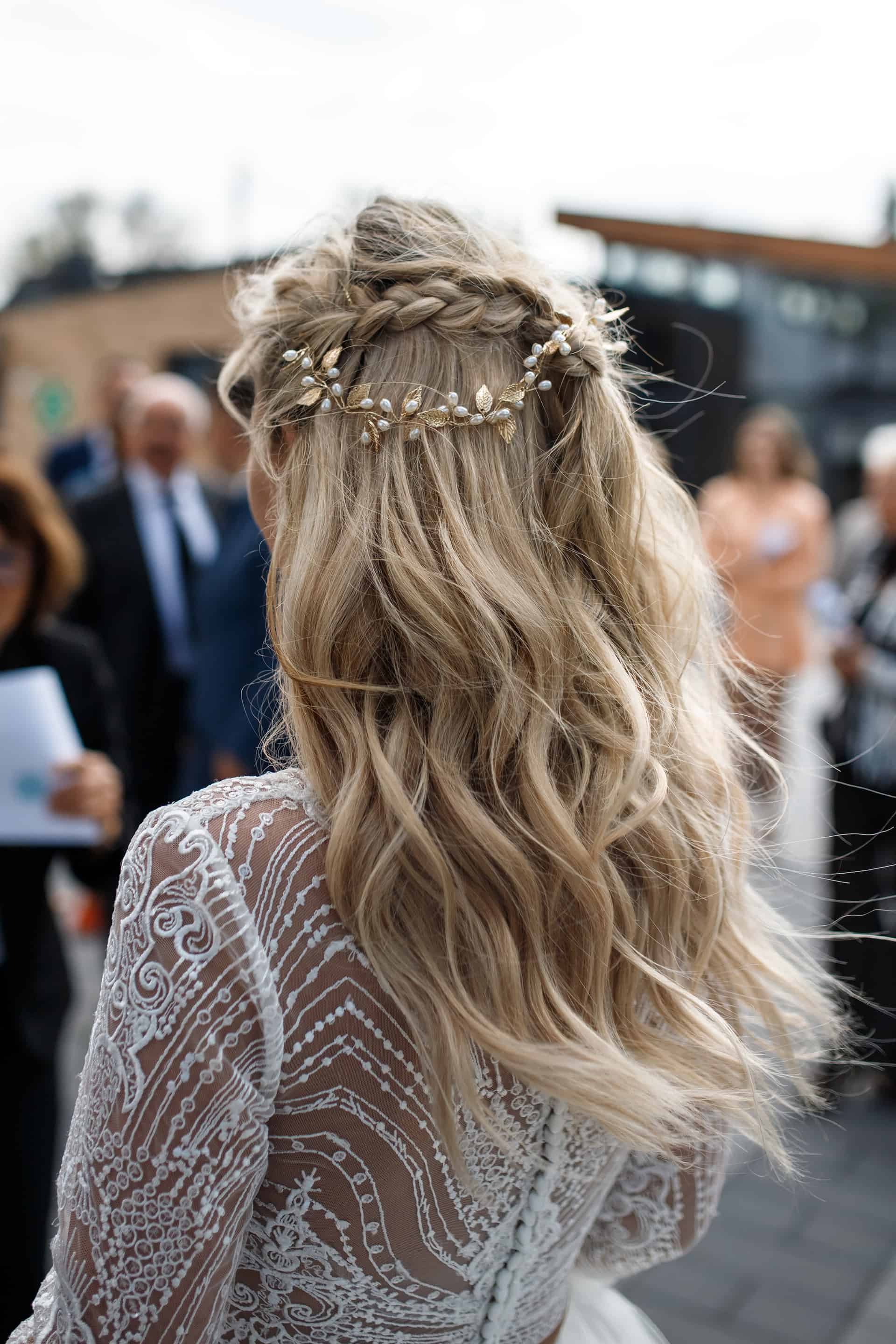 Detail der Brautfrisur von hinten: geflochtene Boho-Steckfrisur mit goldenem Haarschmuck aus Blättern und Perlen.