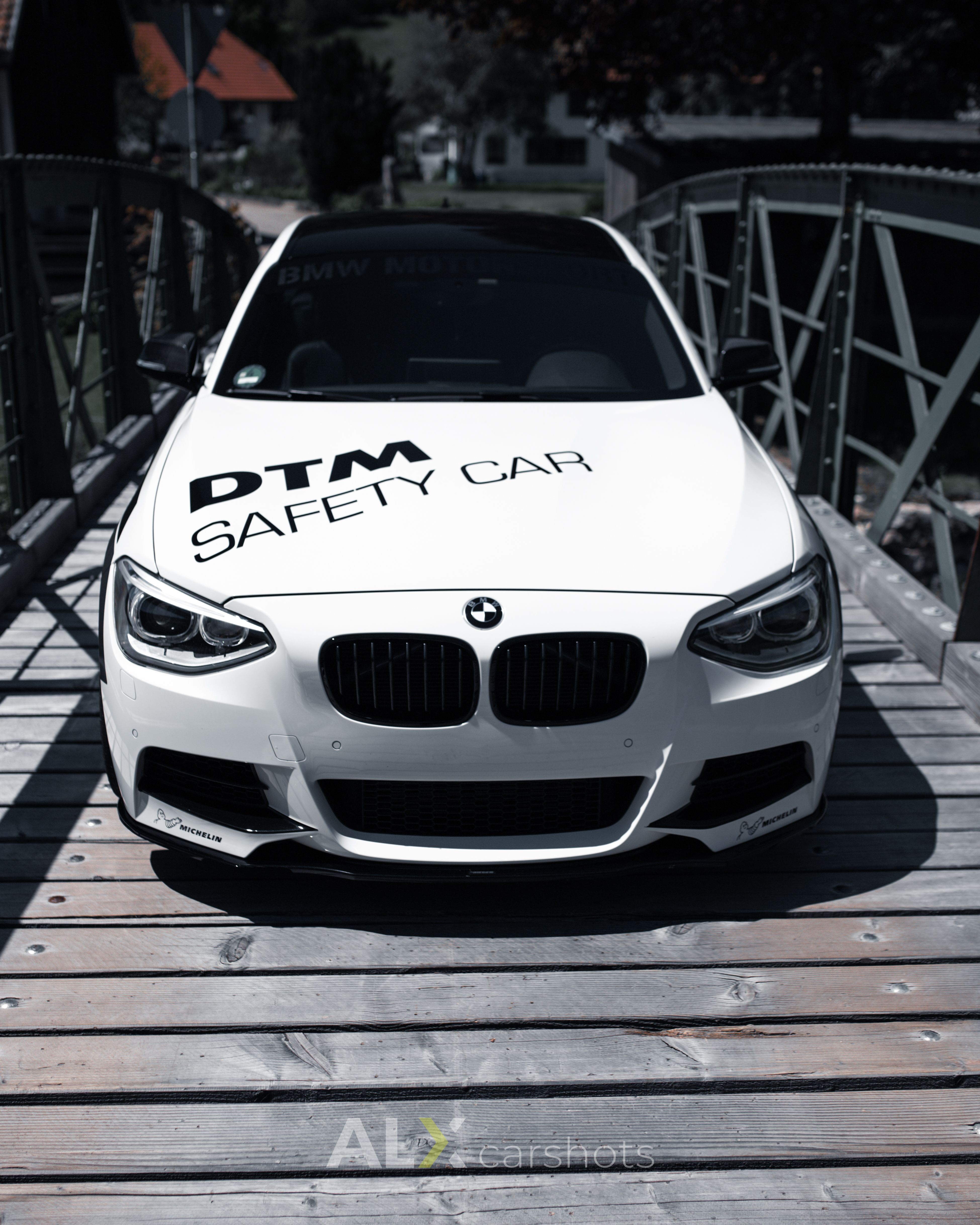 Weißer BMW 1er mit DTM-Safety-Car-Beschriftung frontal auf einer Stahlbrücke im Schwarzwald