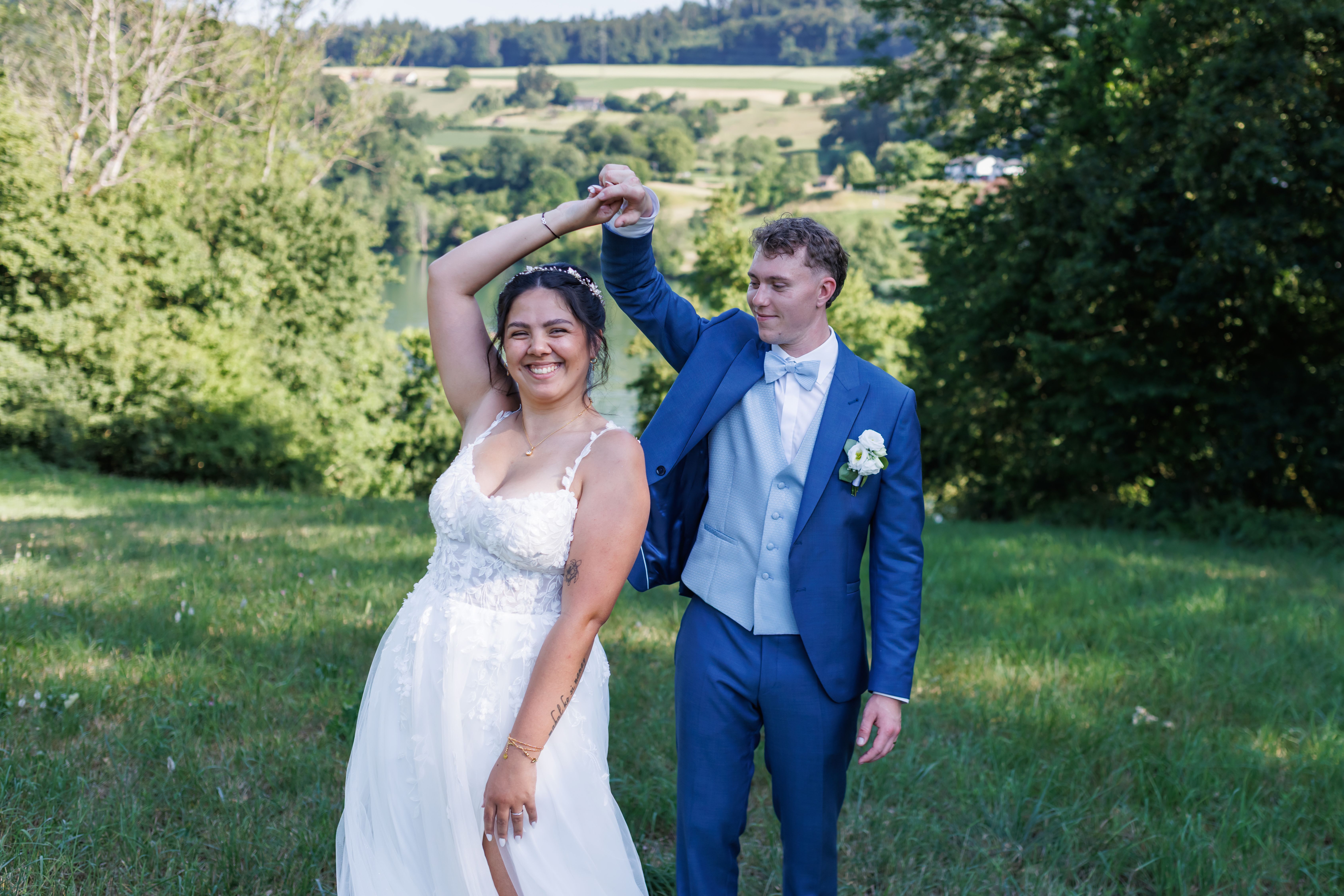 Stefanie und Manuel tanzen ausgelassen mit erhobenen Armen im Feld