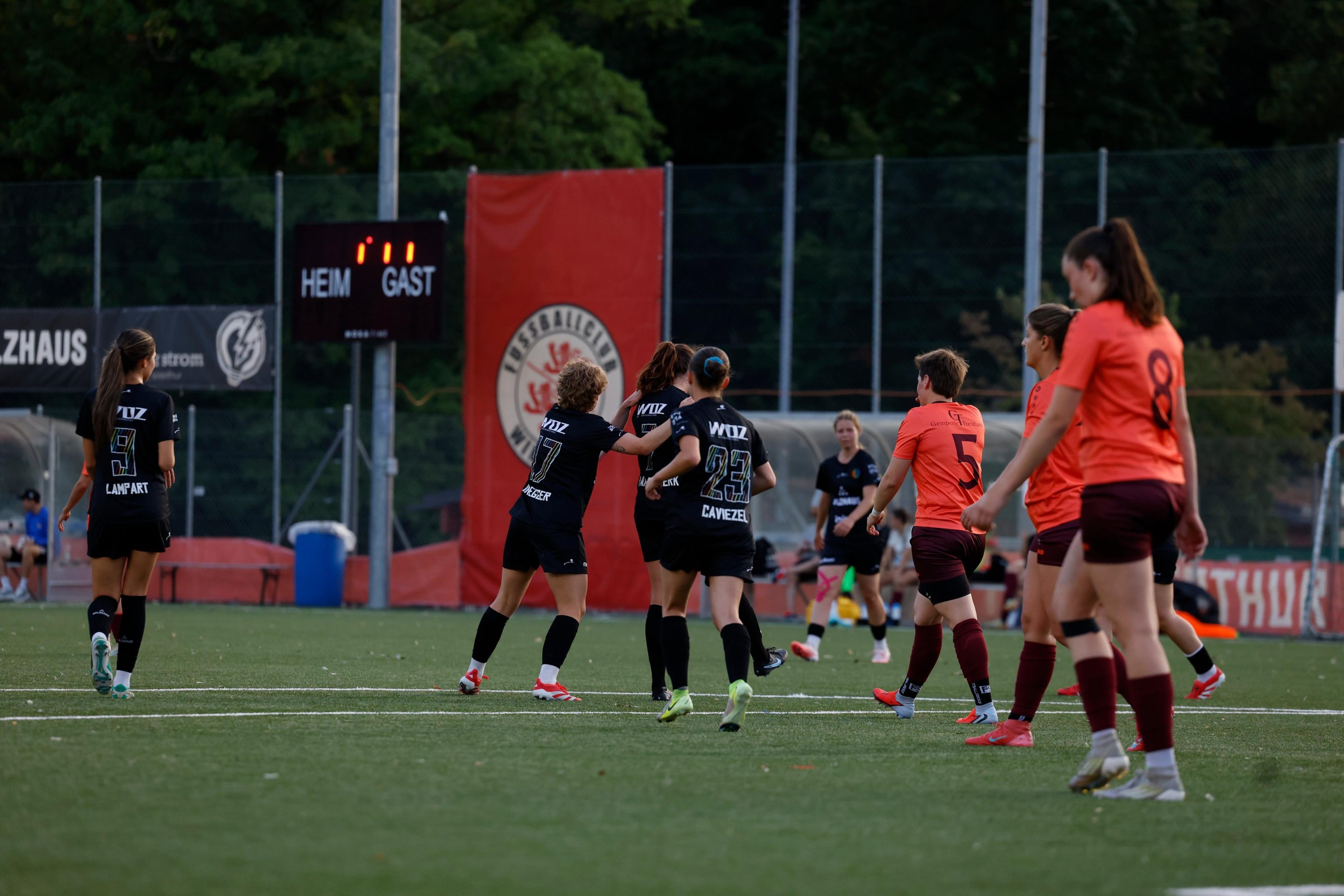 Elena Van Niekerk, Kaya Lindegger und Simona Caviezel vom FC Winterthur bejubeln einen Treffer, im Hintergrund die Anzeigetafel im Stadion Schützenwiese.