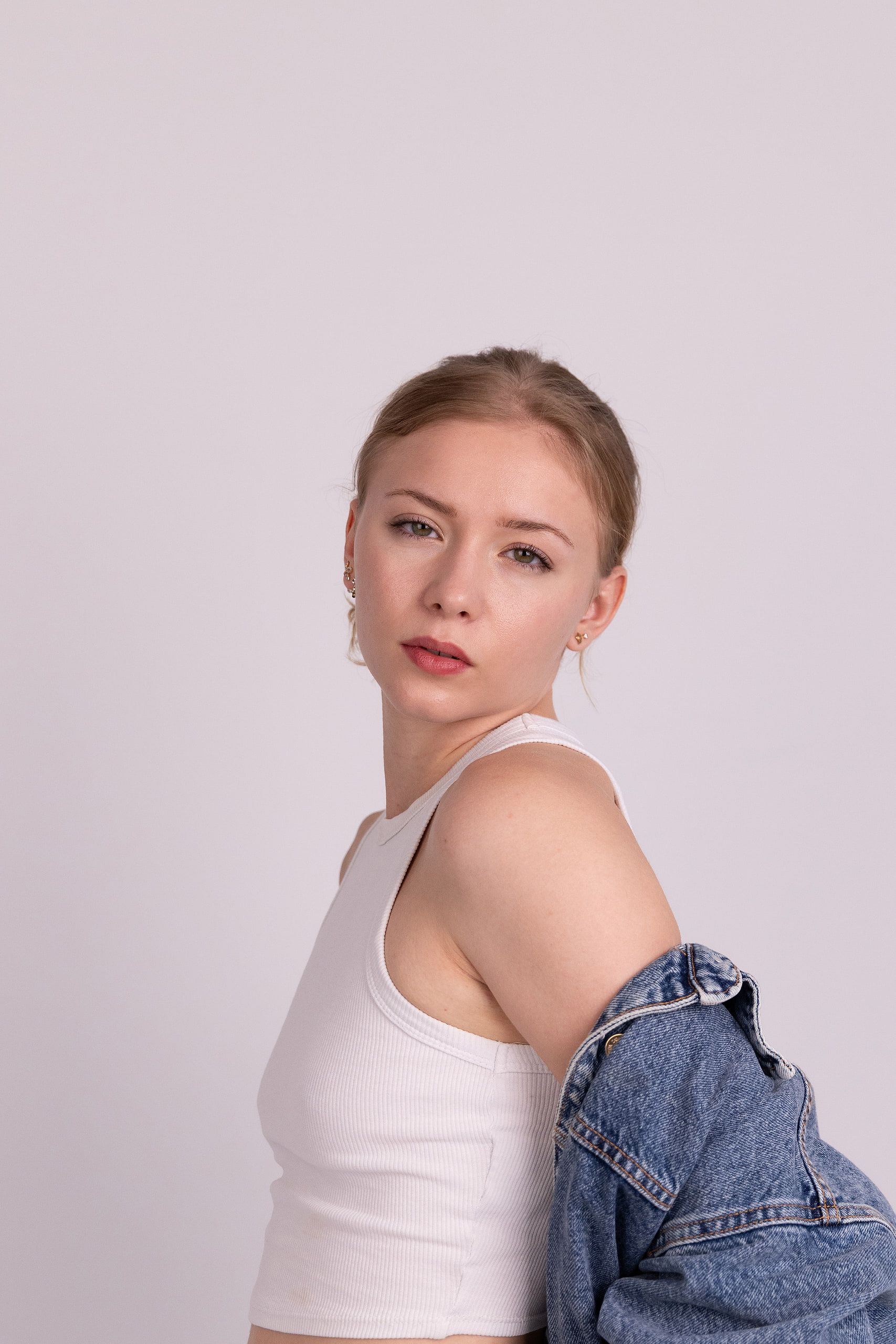 Fashion-Portrait: Annette im weißen Top mit Jeansjacke über der Schulter, im Profil.
