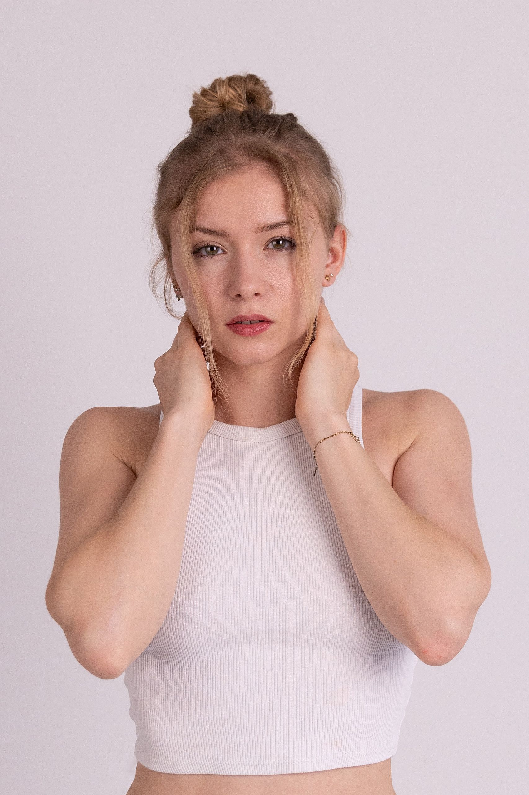 Beauty-Portrait: Annette im weißen Croptop, die Hände am Nacken, das Haar hochgesteckt.