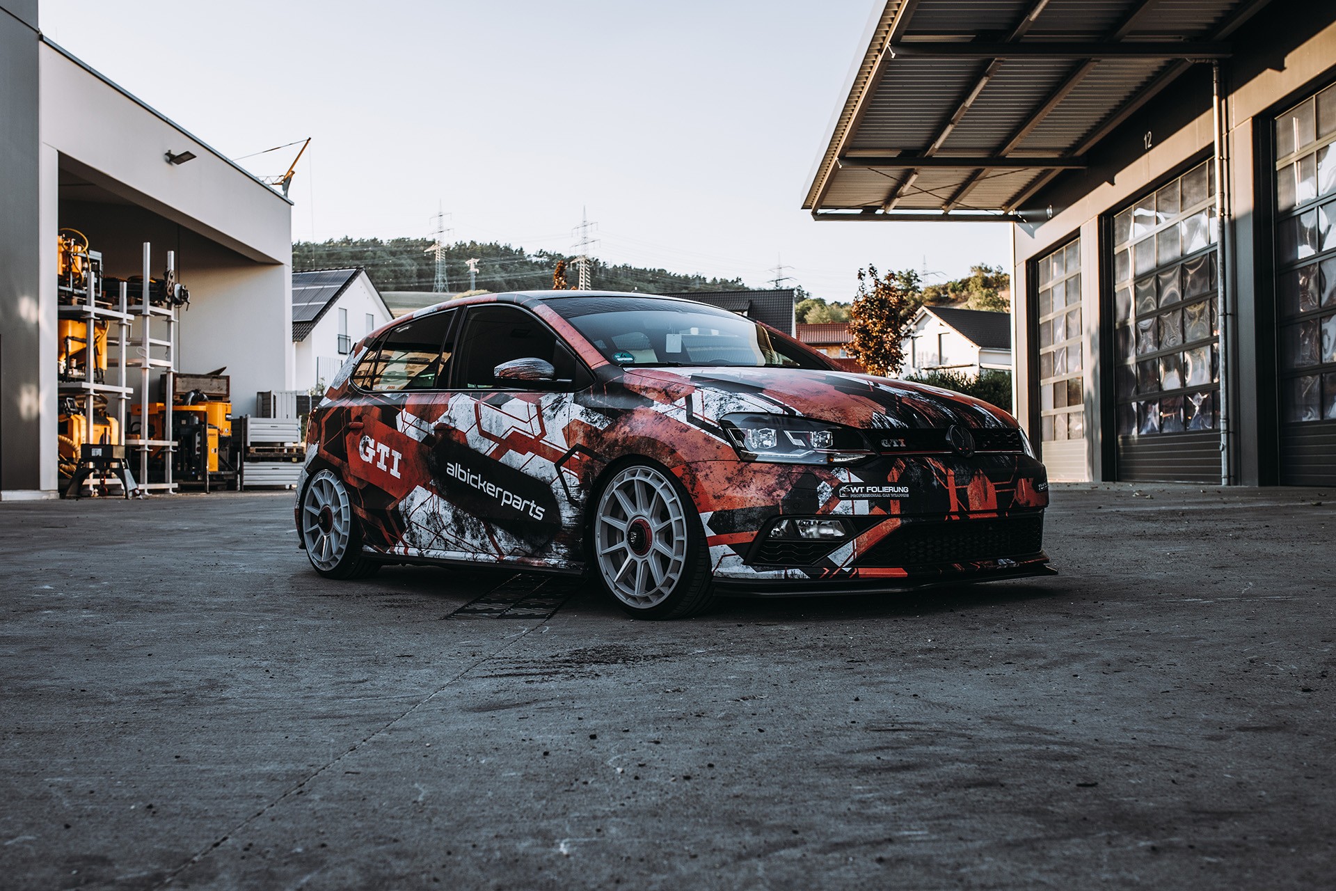 Vollfolierter VW Polo GTI in Schwarz, Rot und Weiß vor Gewerbehallen im Hochschwarzwald
