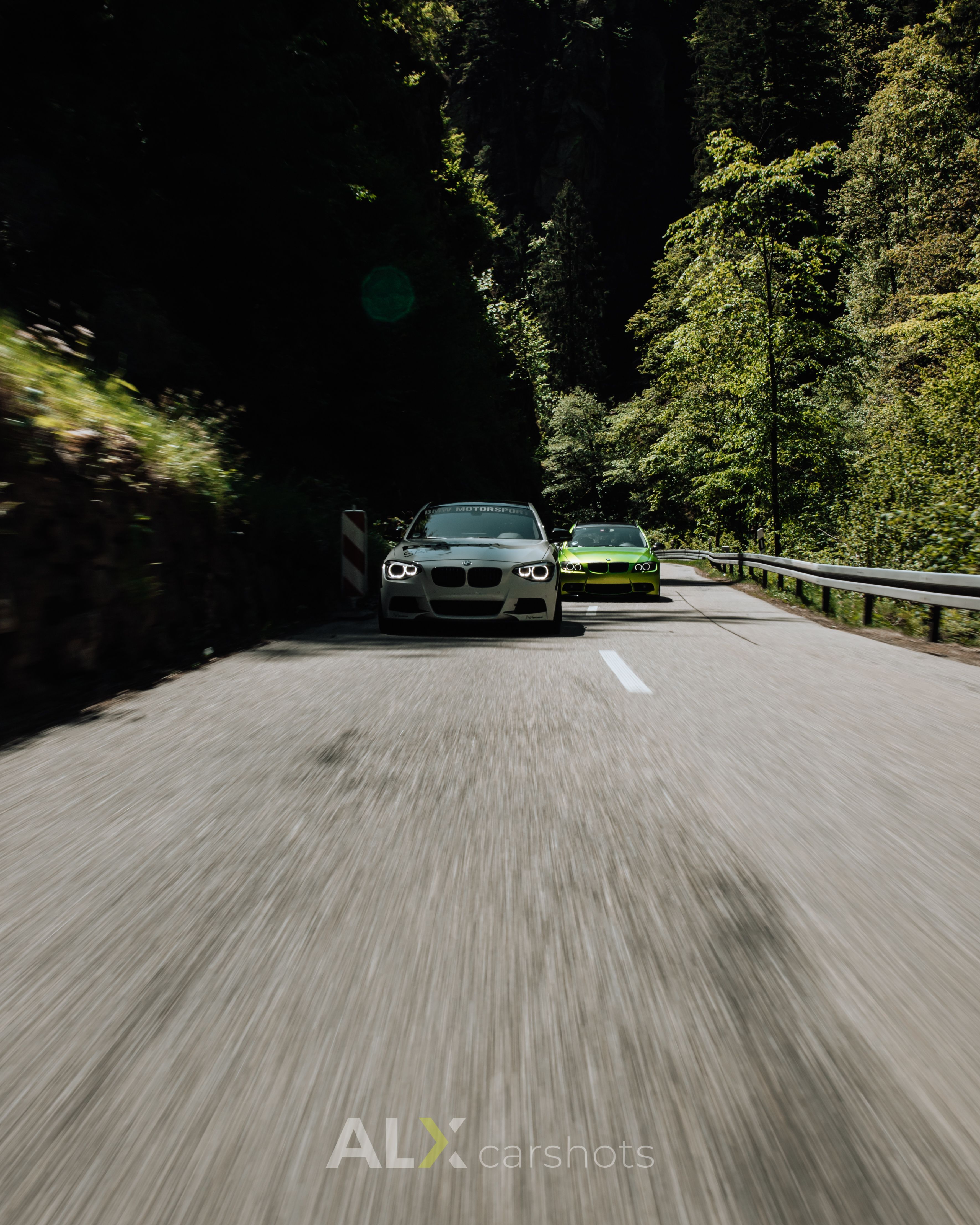 Weißer BMW 1er und grüner BMW als Rollingshot in einer engen Schluchtstraße im Schwarzwald