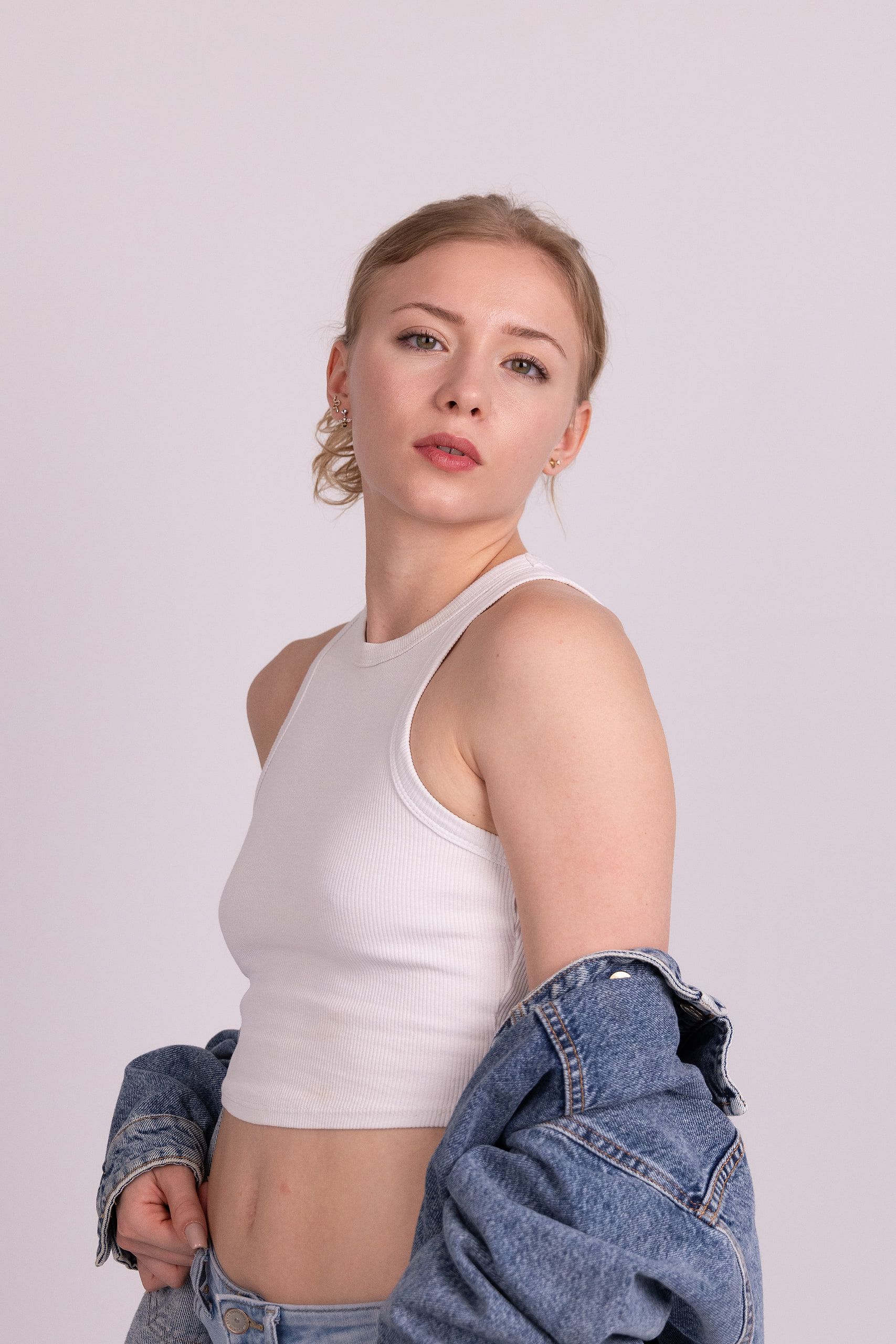 Fashion-Portrait: Annette im weißen Top, die Jeansjacke um die Hüften, direkter Blick.