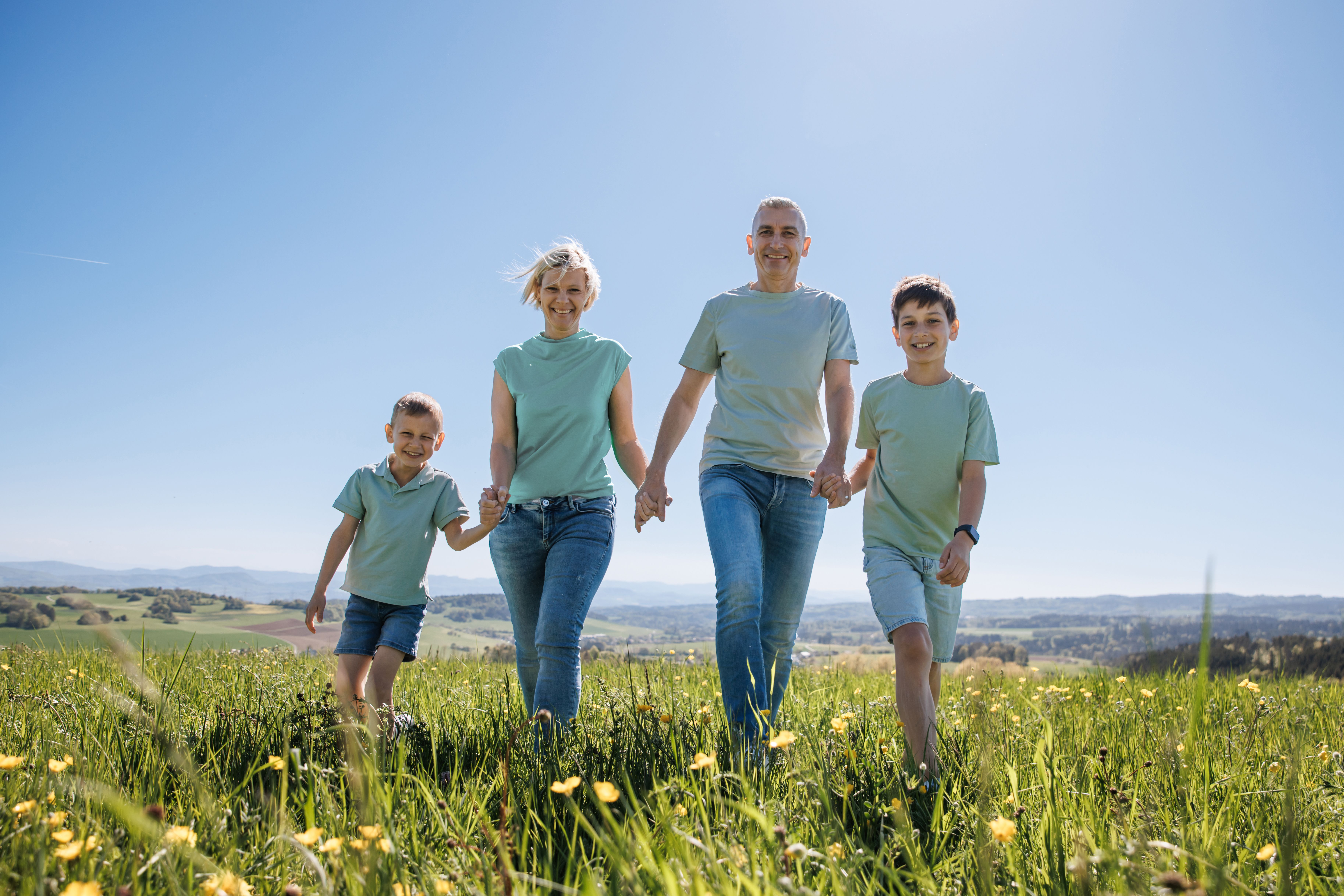 Familie geht Hand in Hand über eine blühende Frühlingswiese am Hochrhein