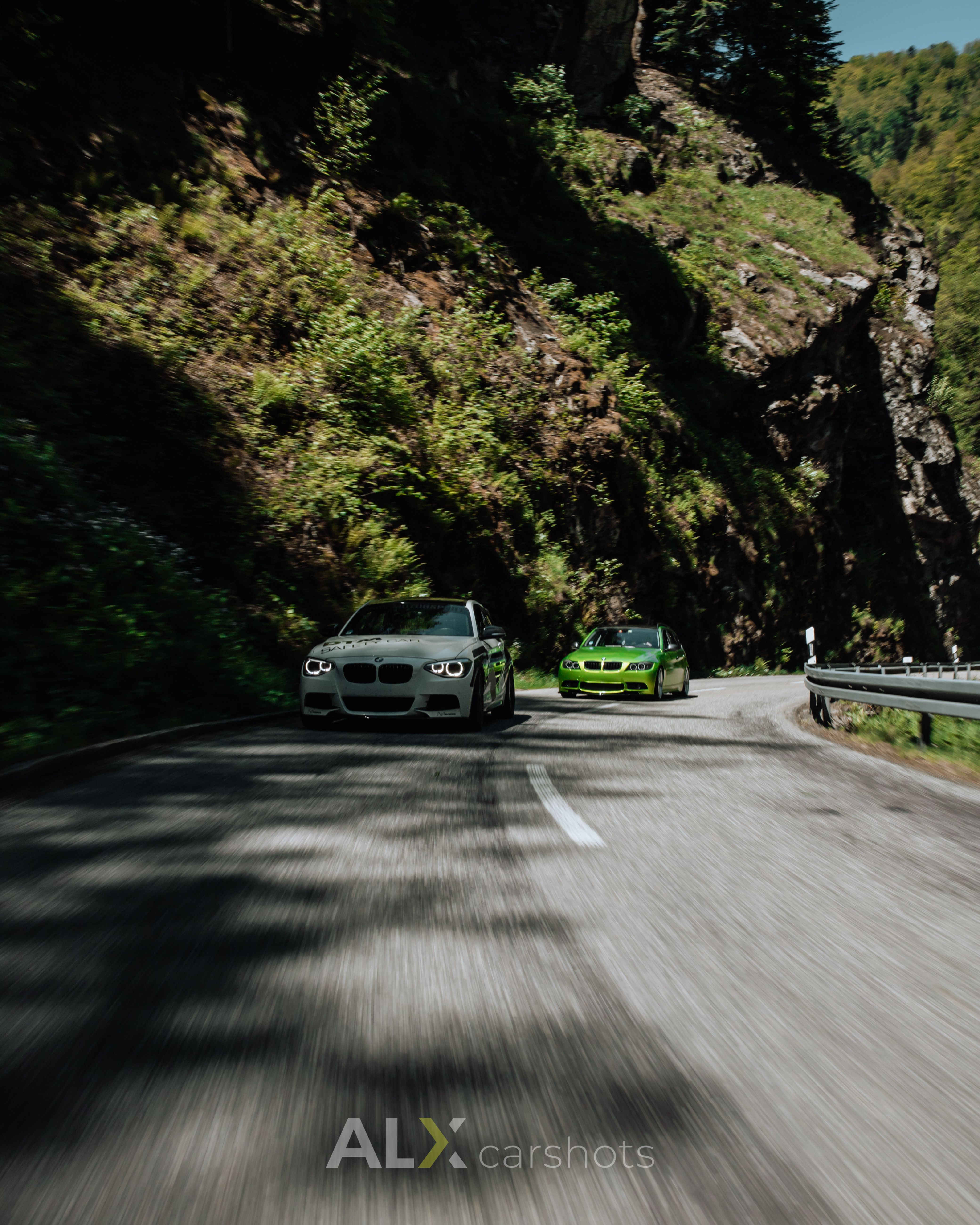 Weißer BMW 5er und grüner BMW als Rollingshot in einer Schwarzwald-Schlucht mit Lichtflecken auf dem Asphalt