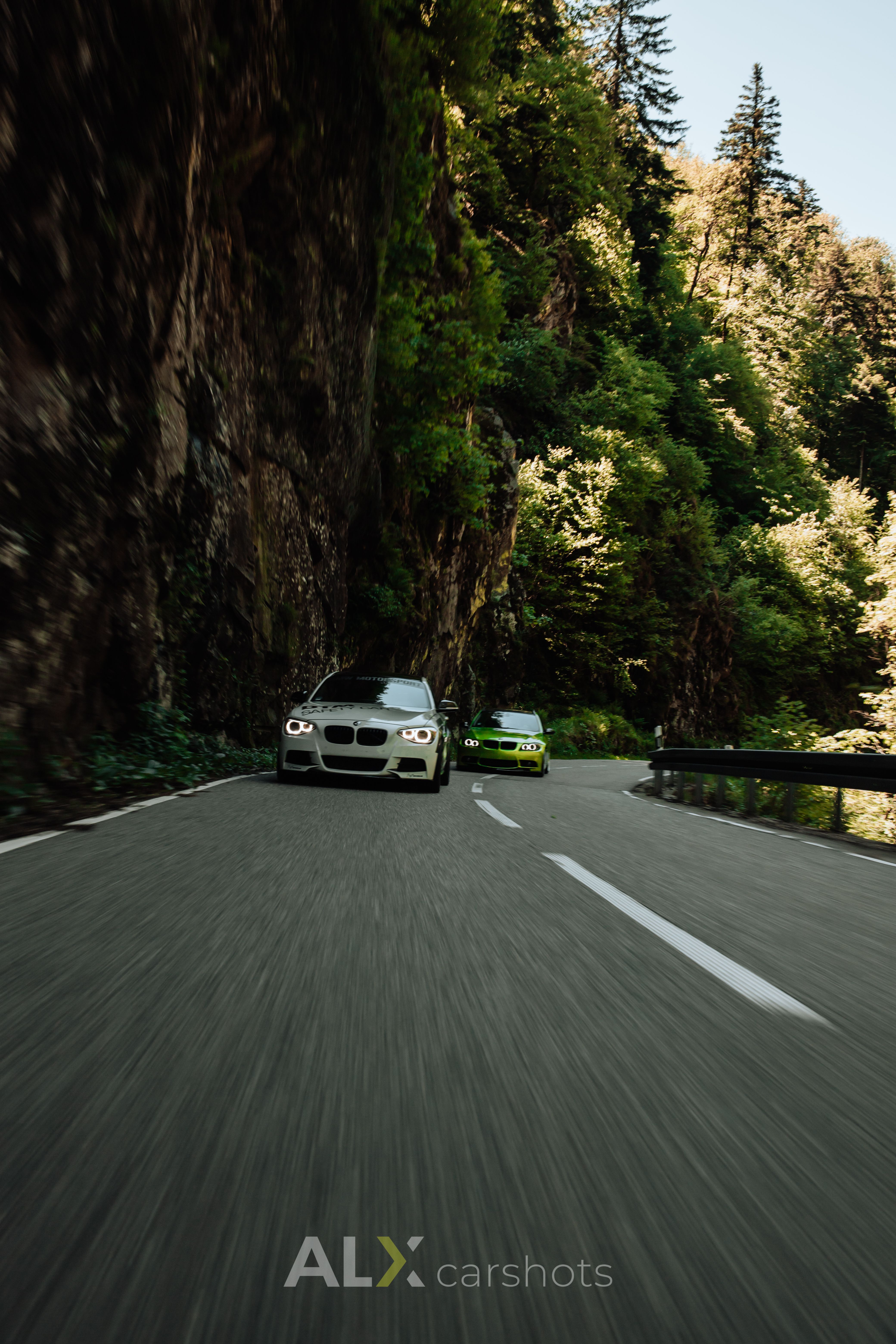 Grüner BMW als Rollingshot in einer schattigen Felsschlucht im Schwarzwald mit starker Bewegungsunschärfe