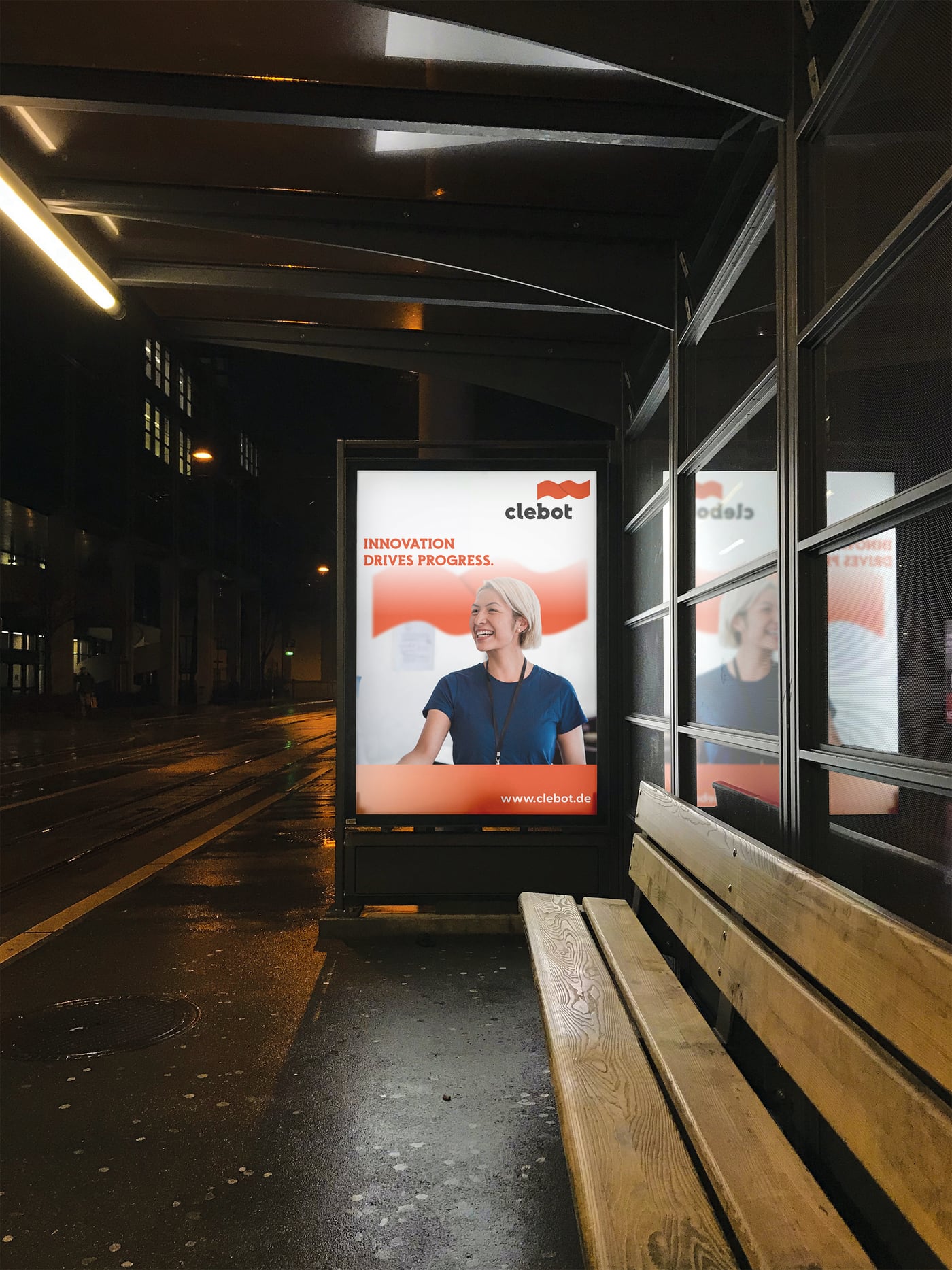 Beleuchtetes Clebot Citylight-Plakat an einer Bushaltestelle bei Nacht.