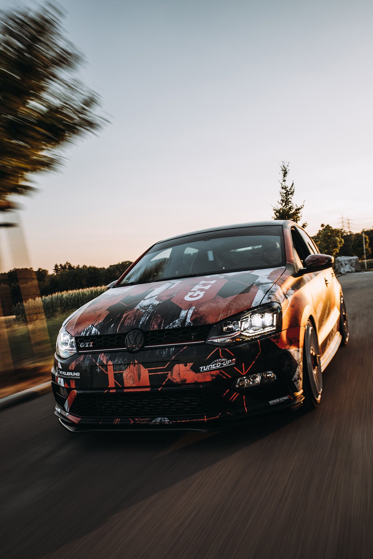 Rollingshot: VW Polo GTI in Fahrt auf einer Landstraße bei Sonnenuntergang