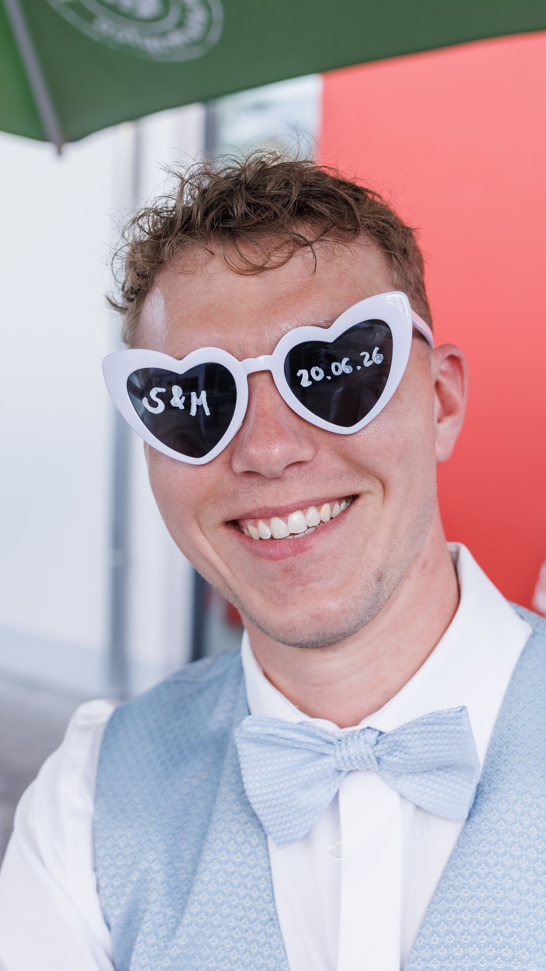 Manuel mit weißer Herzchen-Sonnenbrille, auf den Gläsern die Initialen S und M sowie das Hochzeitsdatum 20.06.26